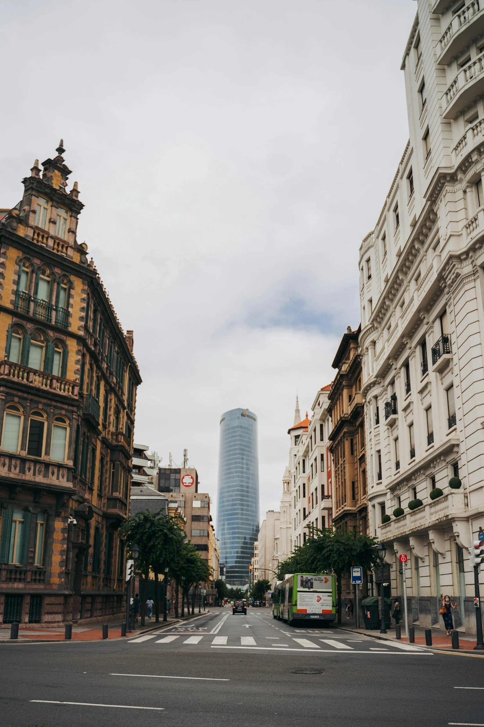 Vista de una calle del centro de Bilbao con edificios históricos y la torre Iberdrola de fondo.