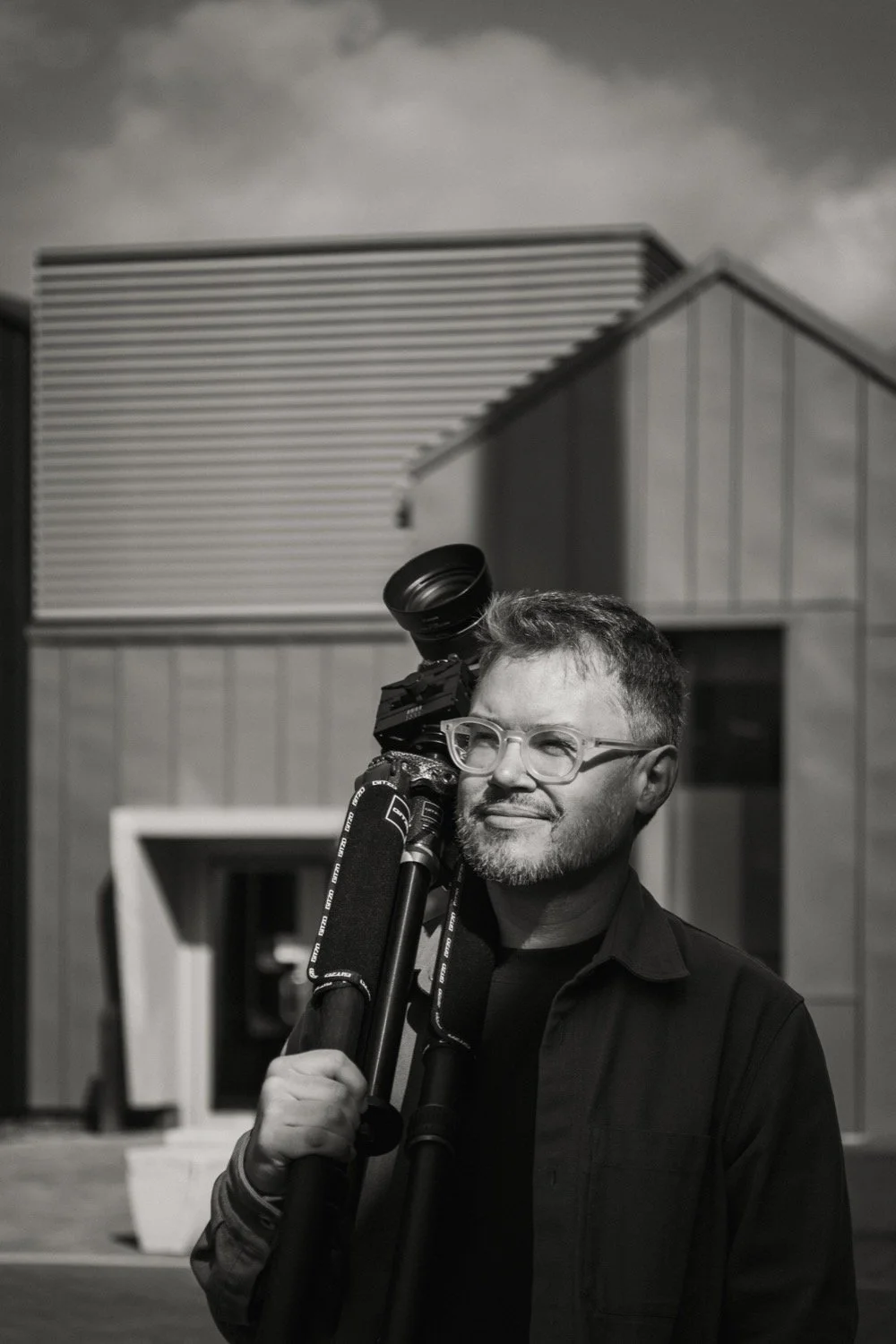 Black and white portrait of architectural photographer Matthew Smith with his camera