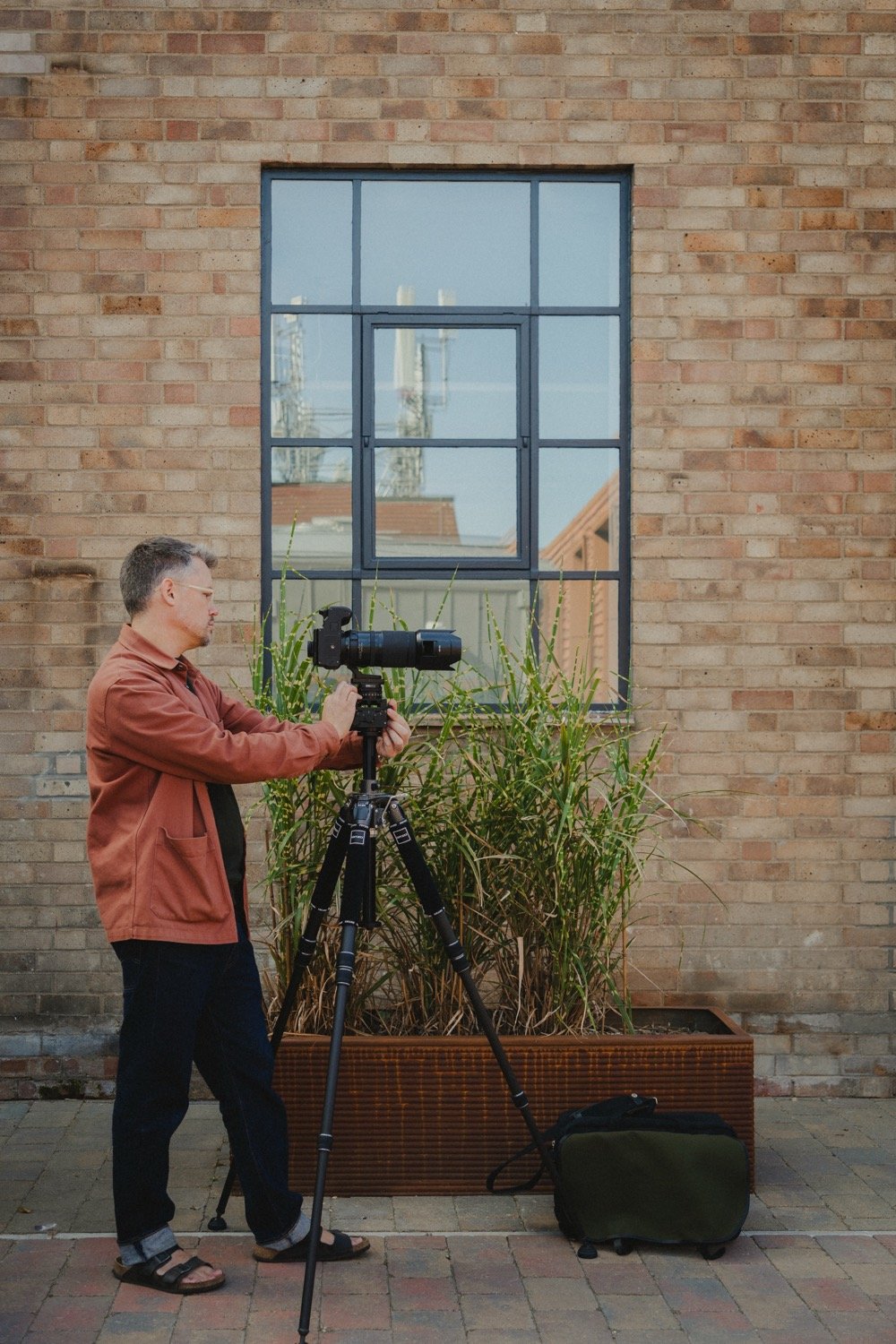 Matthew Smith photographing a steel-framed window in a brick facade at Old Swiss