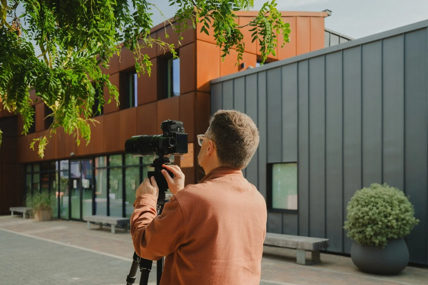 Matthew Smith lining up a shot of grey cladding and a corten-clad building