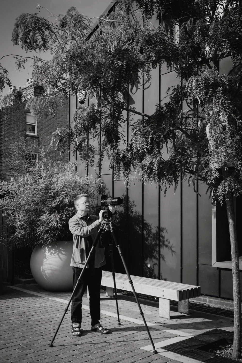 Black and white image of Matthew Smith shooting beside timber-clad buildings at Old Swiss