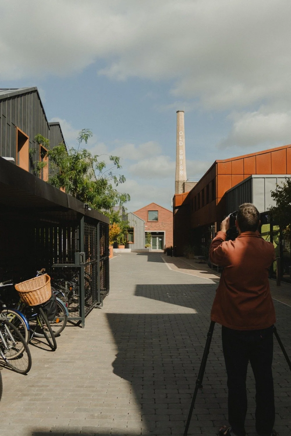 Matthew Smith photographing down a lane past bike racks towards the Swiss Laundry chimney