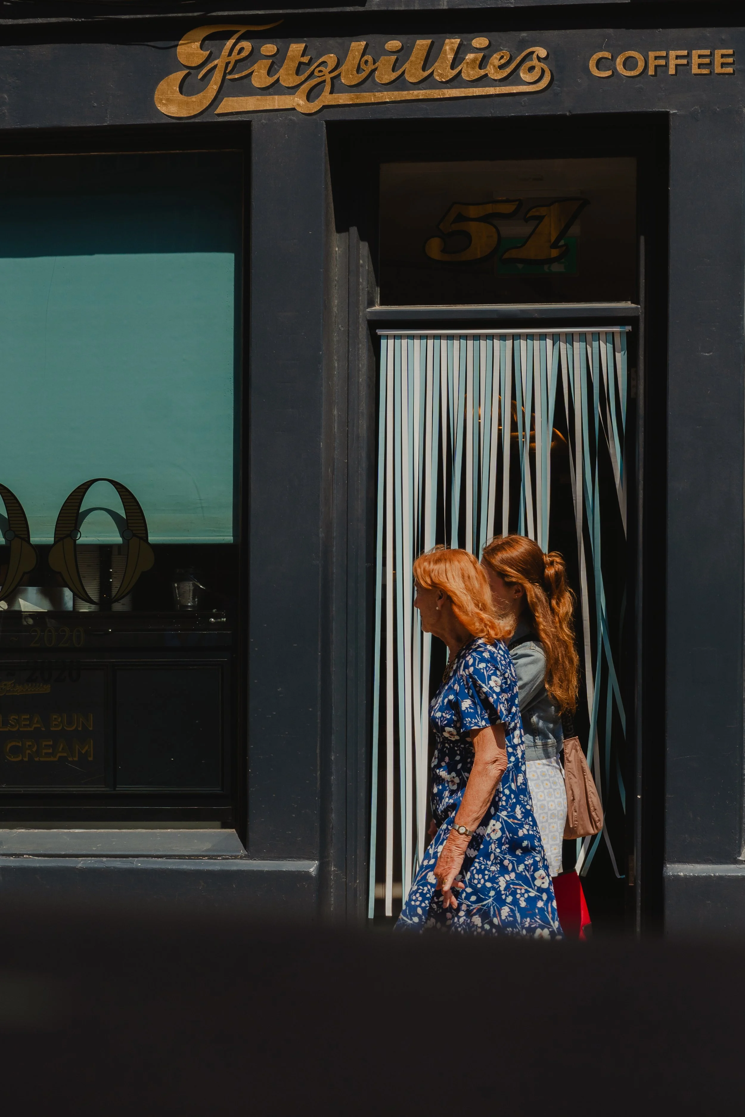 Two women with red hair walking past the storefront of Fitzbillies Coffee.