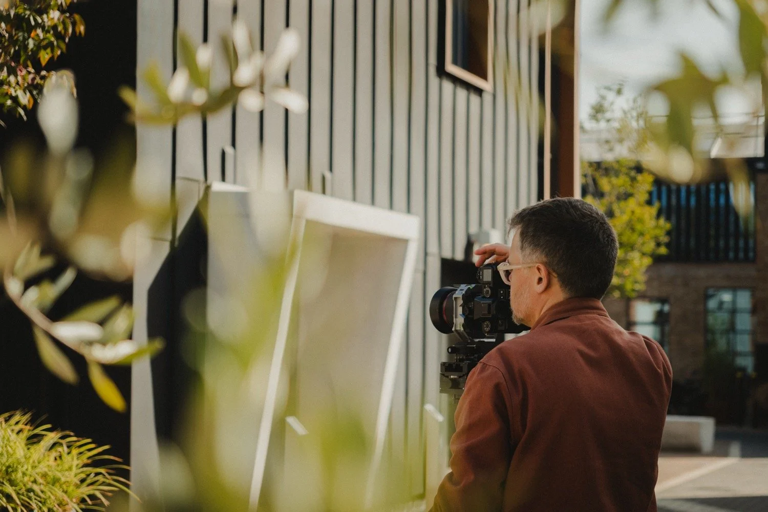 Architectural photographer Matthew Smith filming on a gimbal beside timber cladding at Old Swiss, Cambridge