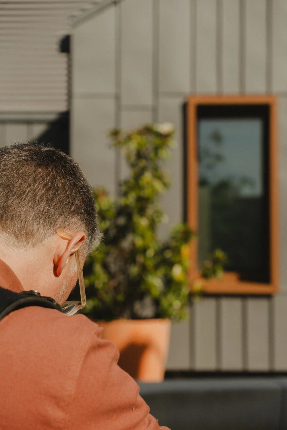 Over-the-shoulder view of Matthew Smith composing a shot of a corten-framed window