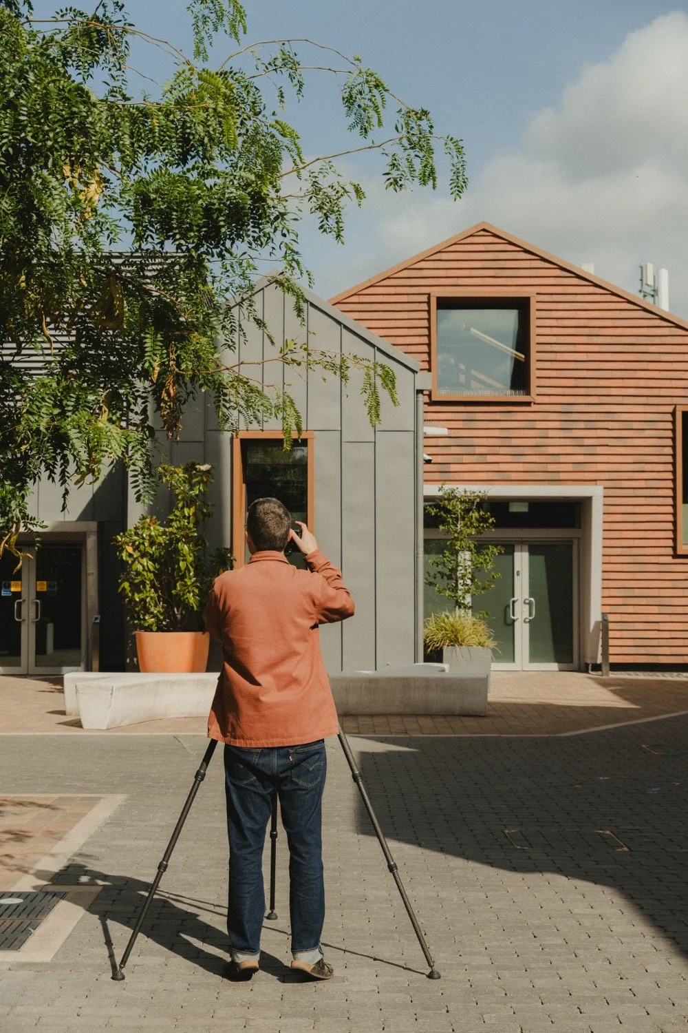 Matthew Smith photographing timber-clad buildings across a courtyard at Old Swiss, Cambridge