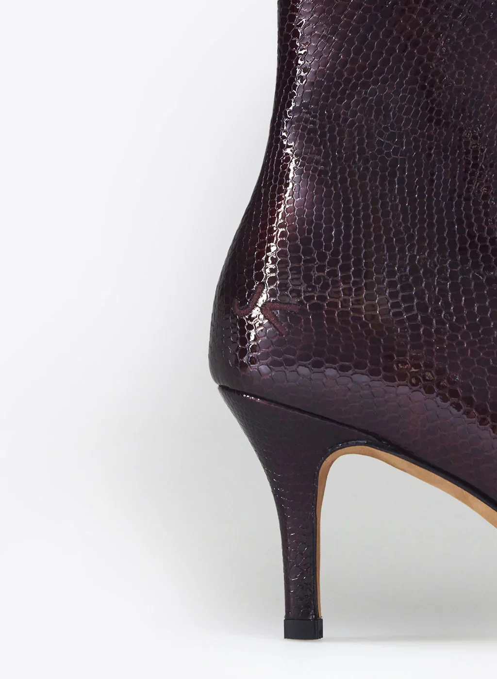 Chaussure à talon haut en cuir effet peau de serpent de couleur violette foncée.