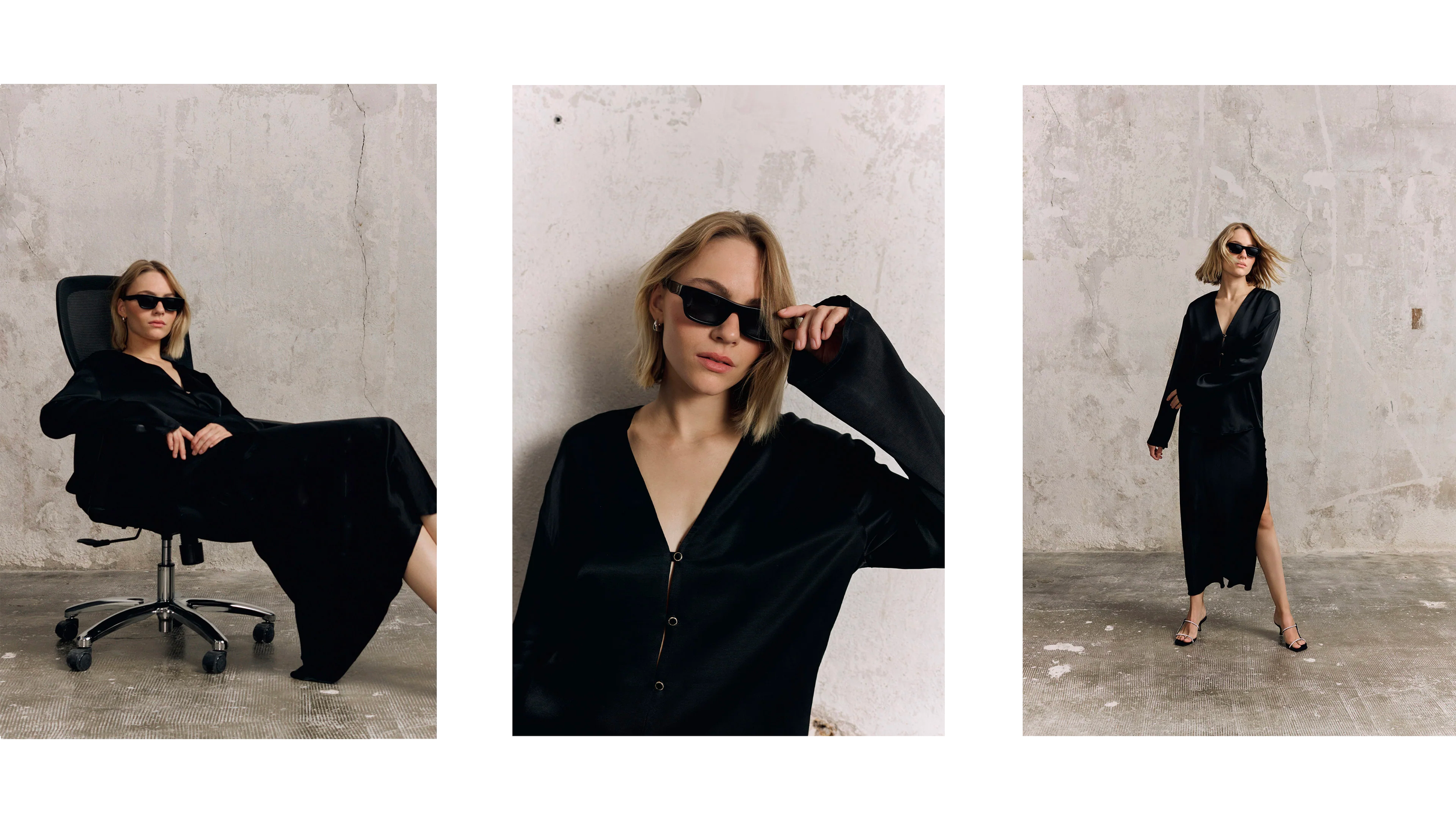 Une femme élégante portant une robe noire avec des sandales à talons, lunettes de soleil noires, pose dans un espace minimaliste avec un mur en béton brut.