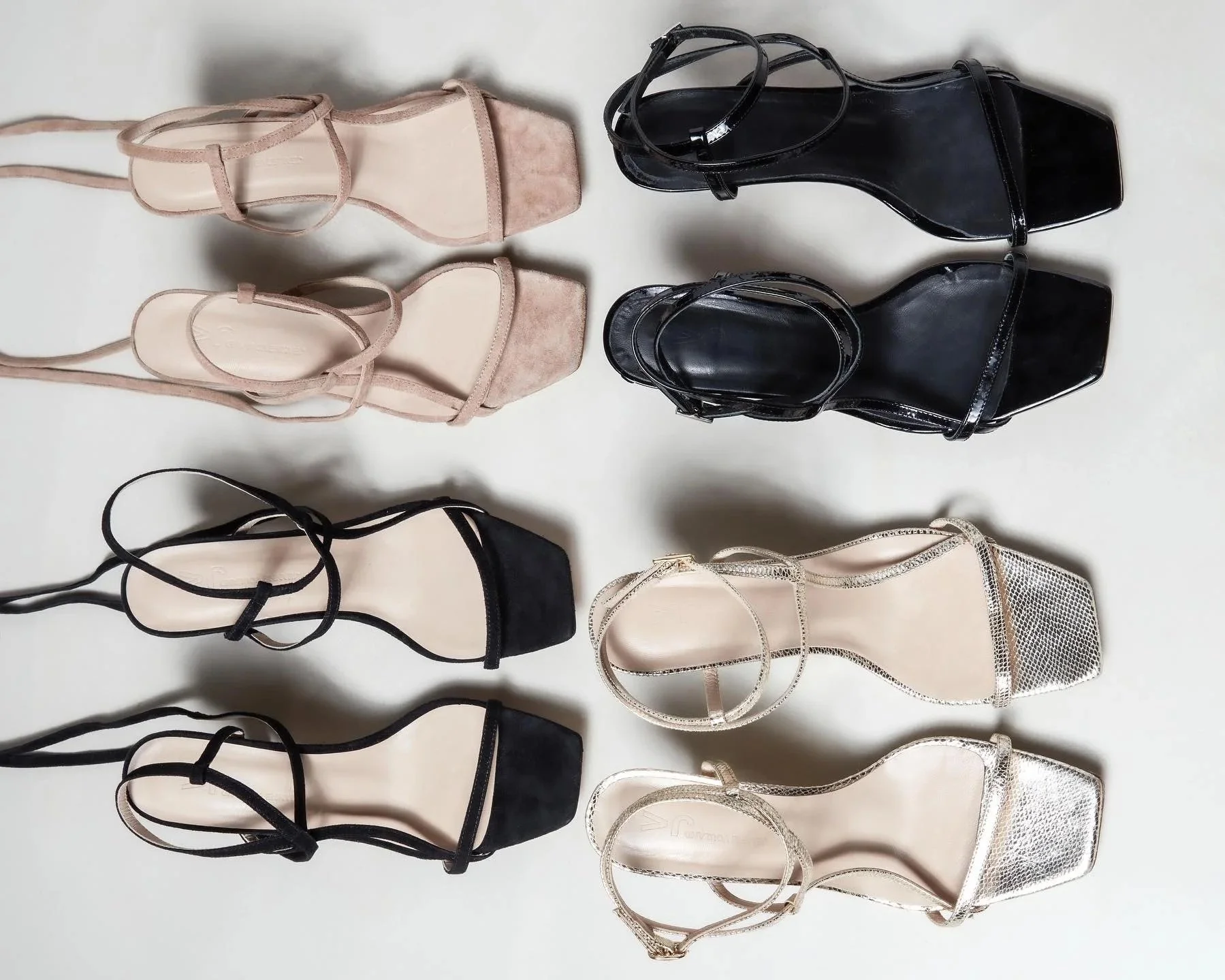 Six paires de sandales à talons hauts de différentes couleurs et styles, alignées sur une surface blanche.