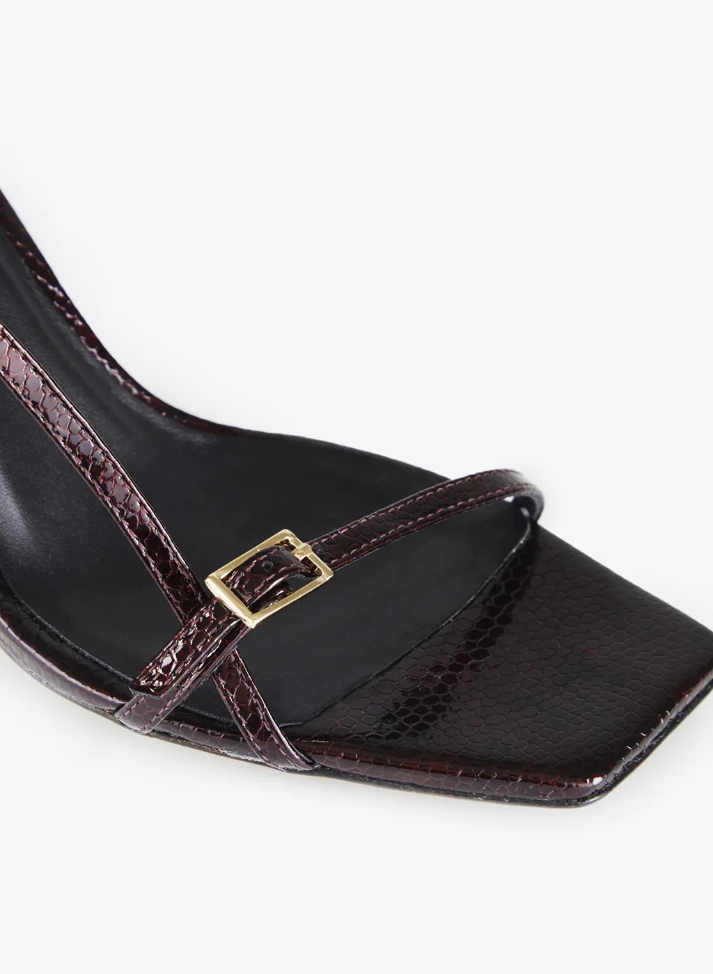 Chaussure à talon avec une finition en faux crocodile, caractérisée par une couleur noire et une bride avec boucle dorée