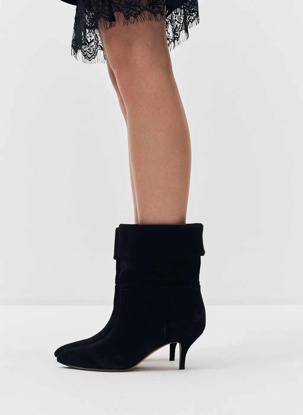 Jambes d'une femme avec des bottes noires à talons hauts et une jupe en dentelle noire