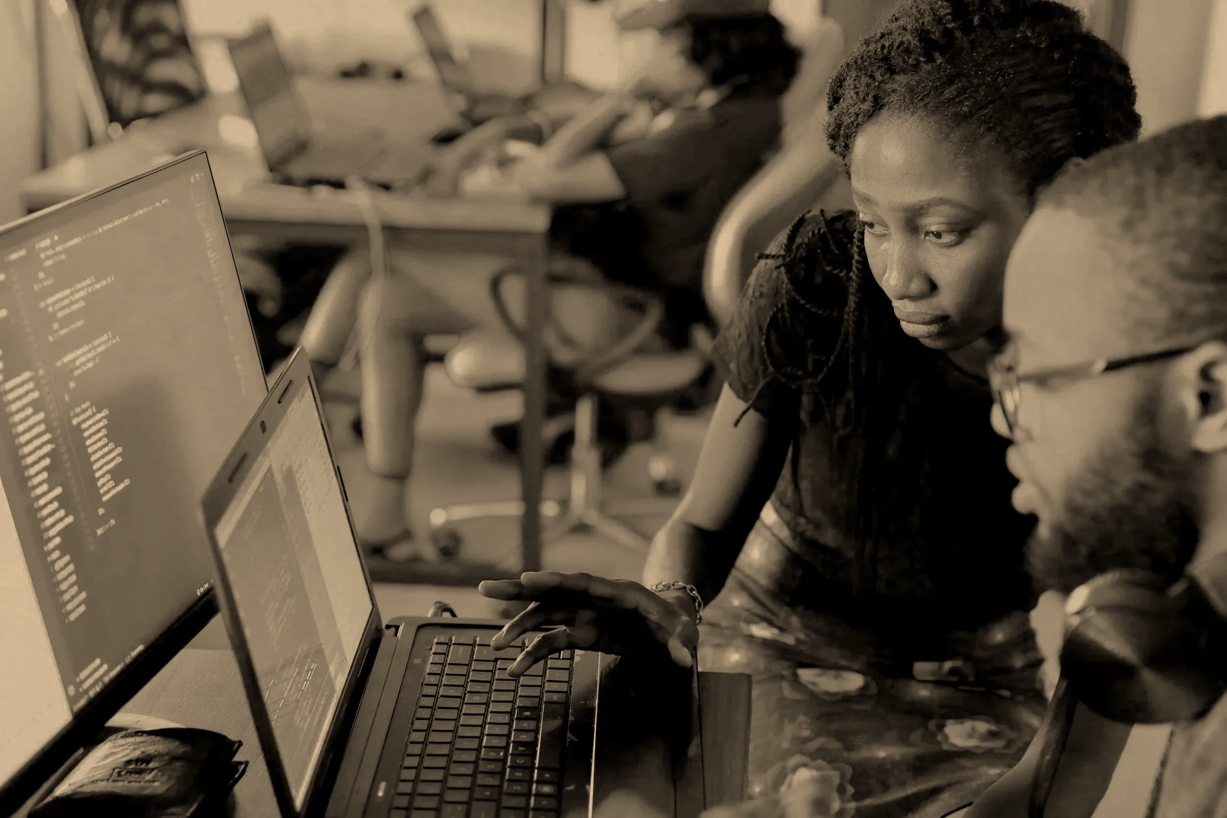 Two people working together on a computer in an office setting.
