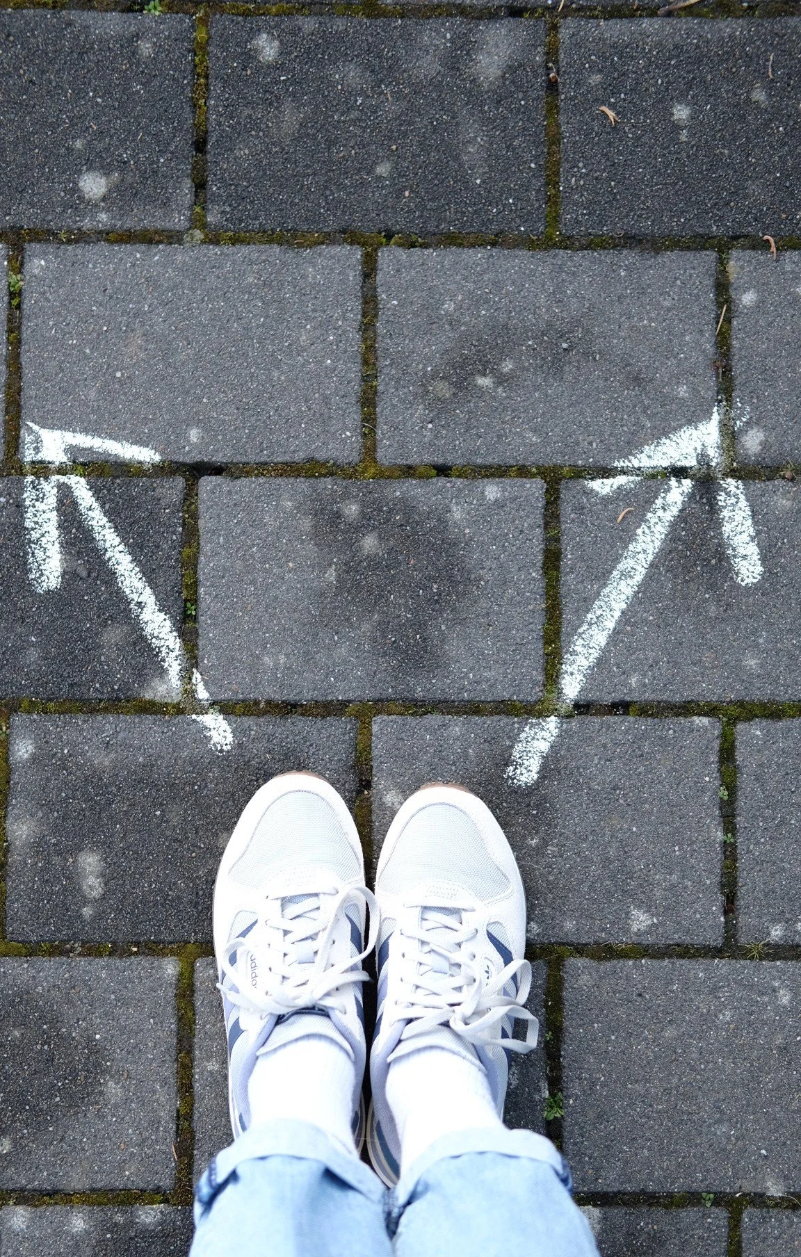 Füße vor zwei Richtungspfeilen symbolisieren bewusste Entscheidungen statt automatischer Reaktionsmuster im Coaching