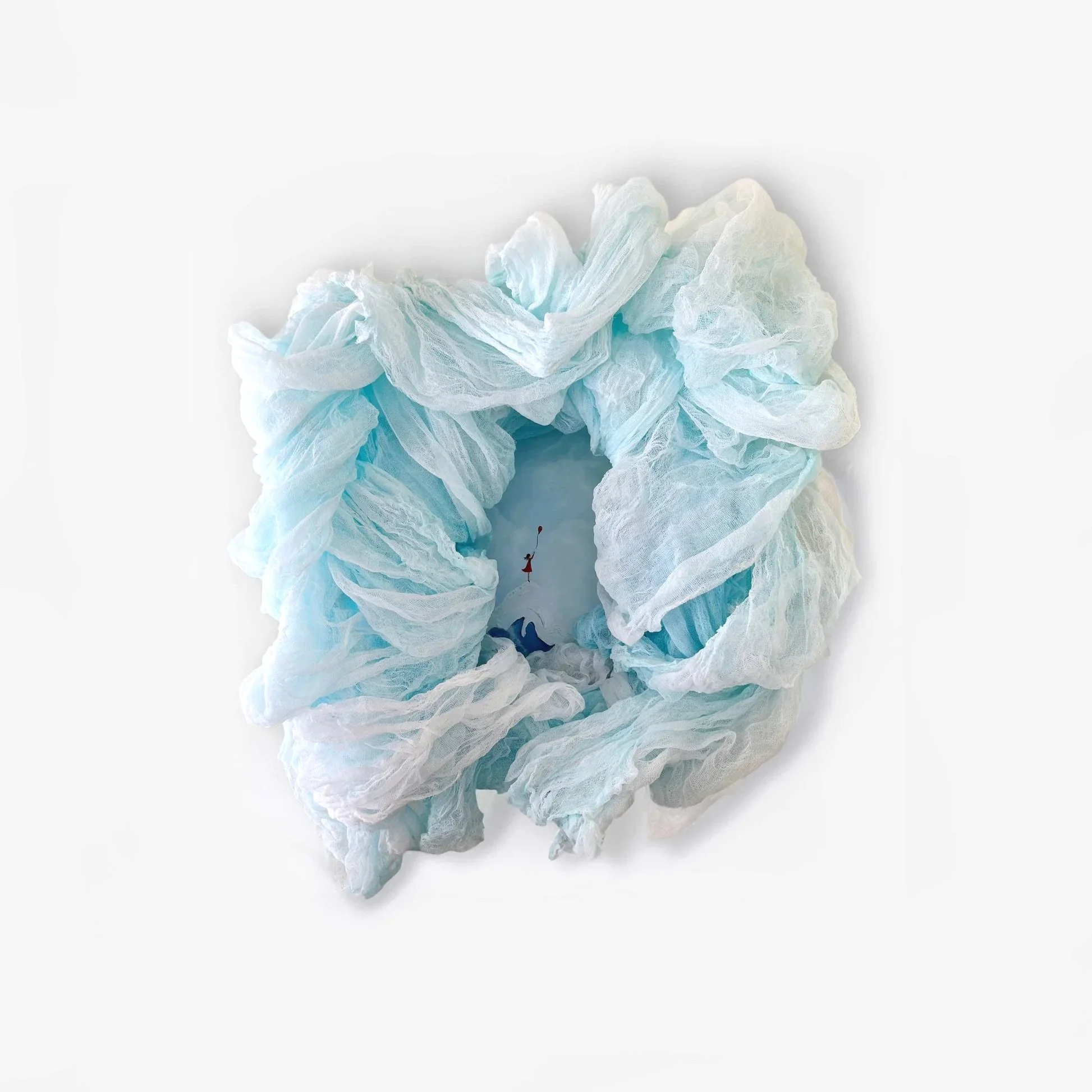 A flower-shaped paper or fabric wreath in white and light blue, with an illustration of a girl holding a balloon in the center.