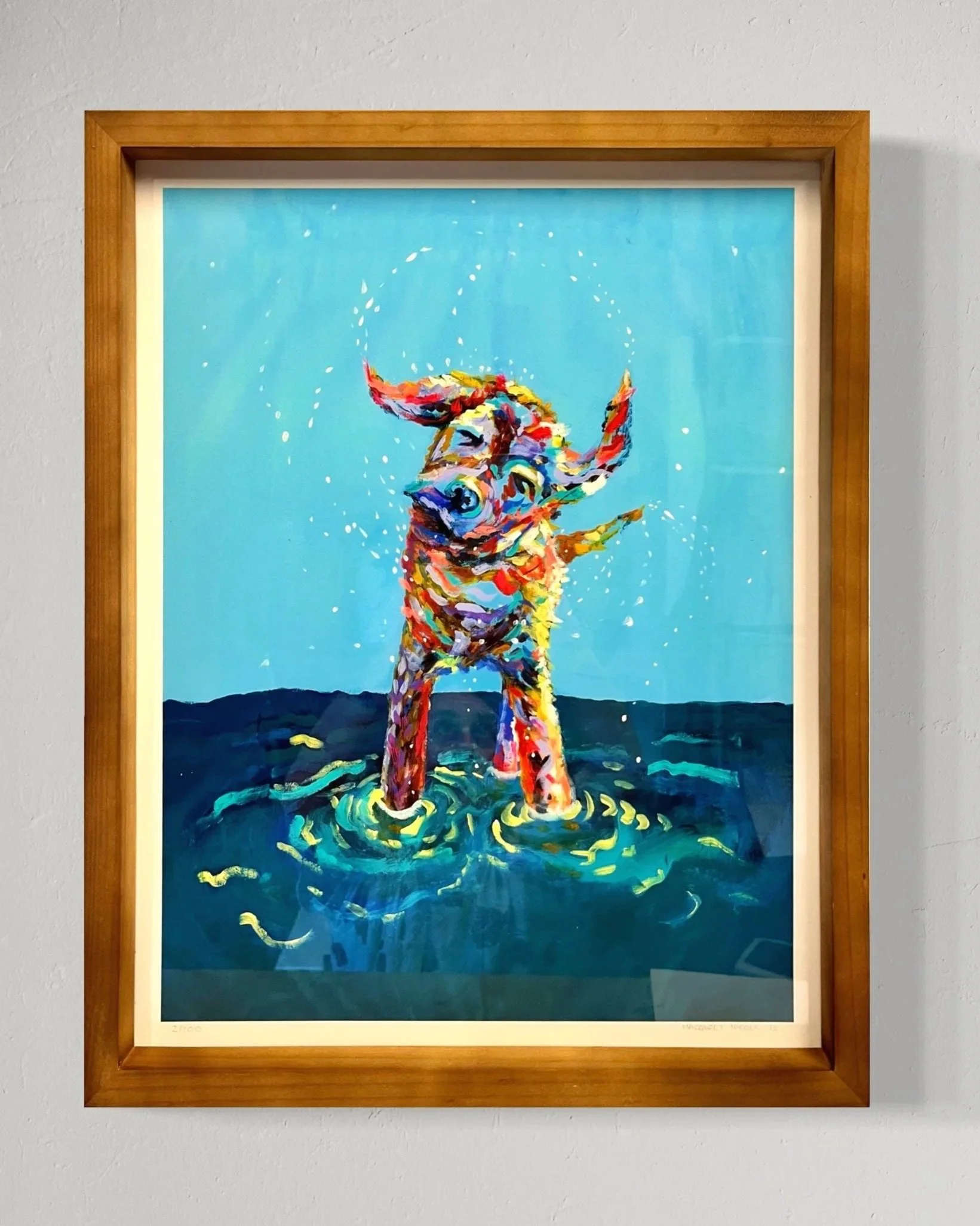 Colorful painting of a dog standing in water with splashes and a bright blue background, framed in wood.
