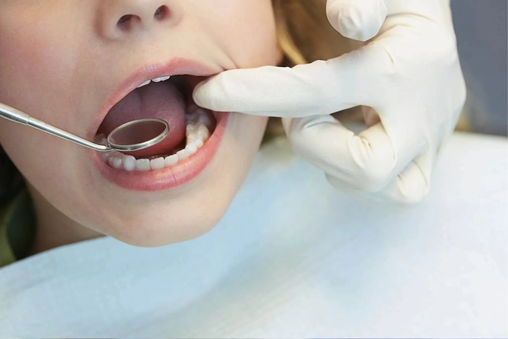 Un dentiste examine la bouche d'une jeune femme dans un cabinet dentaire, portant des gants en latex.