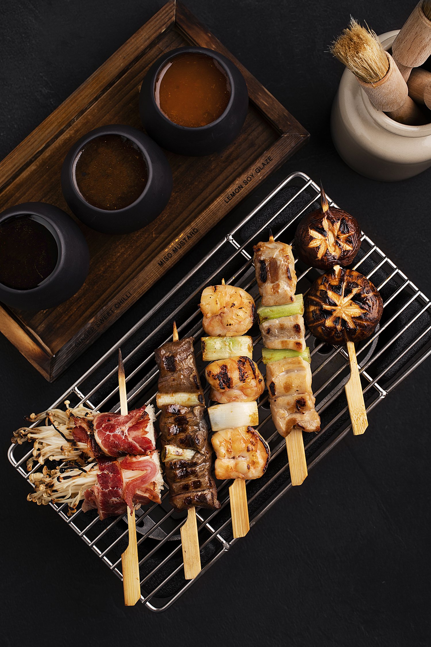 Assorted grilled skewers with vegetables and seafood on a grill rack