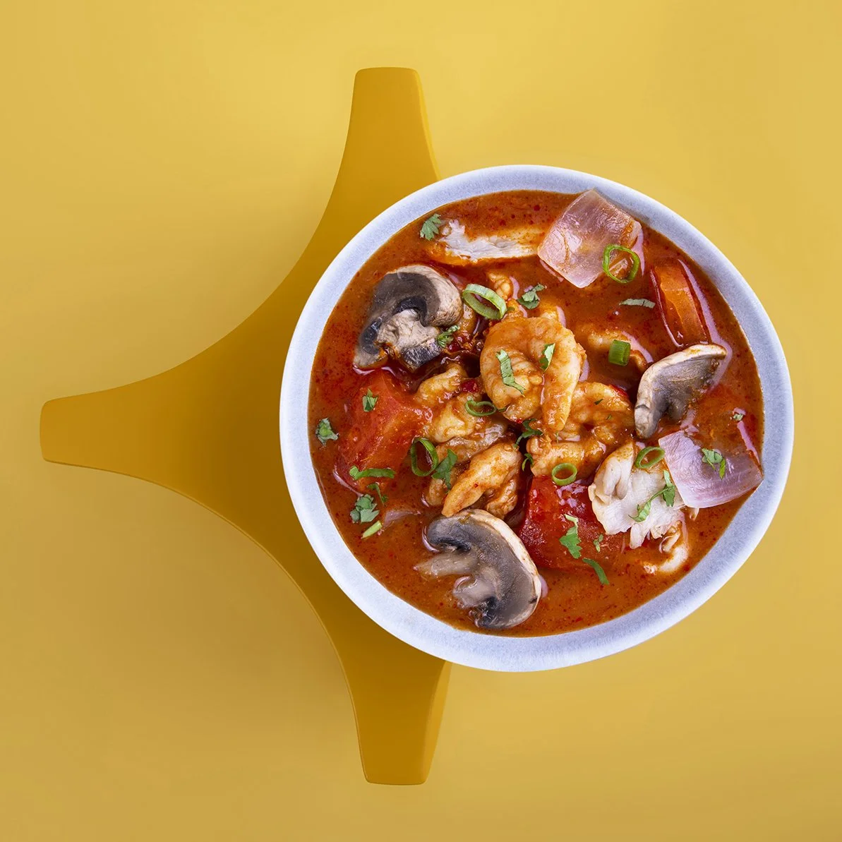 A bowl of shrimp gumbo with mushrooms, chopped green onions, red bell peppers, and ham shot for Ananas