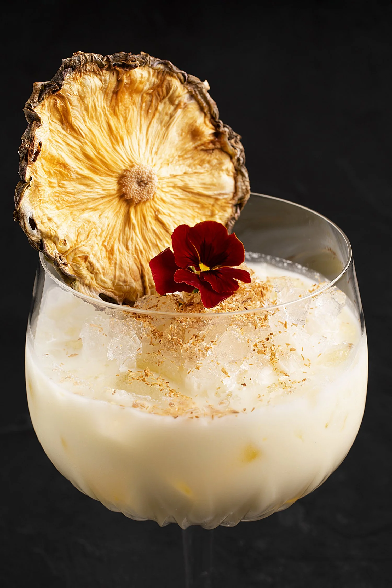 A cocktail garnished with a large dried pineapple slice