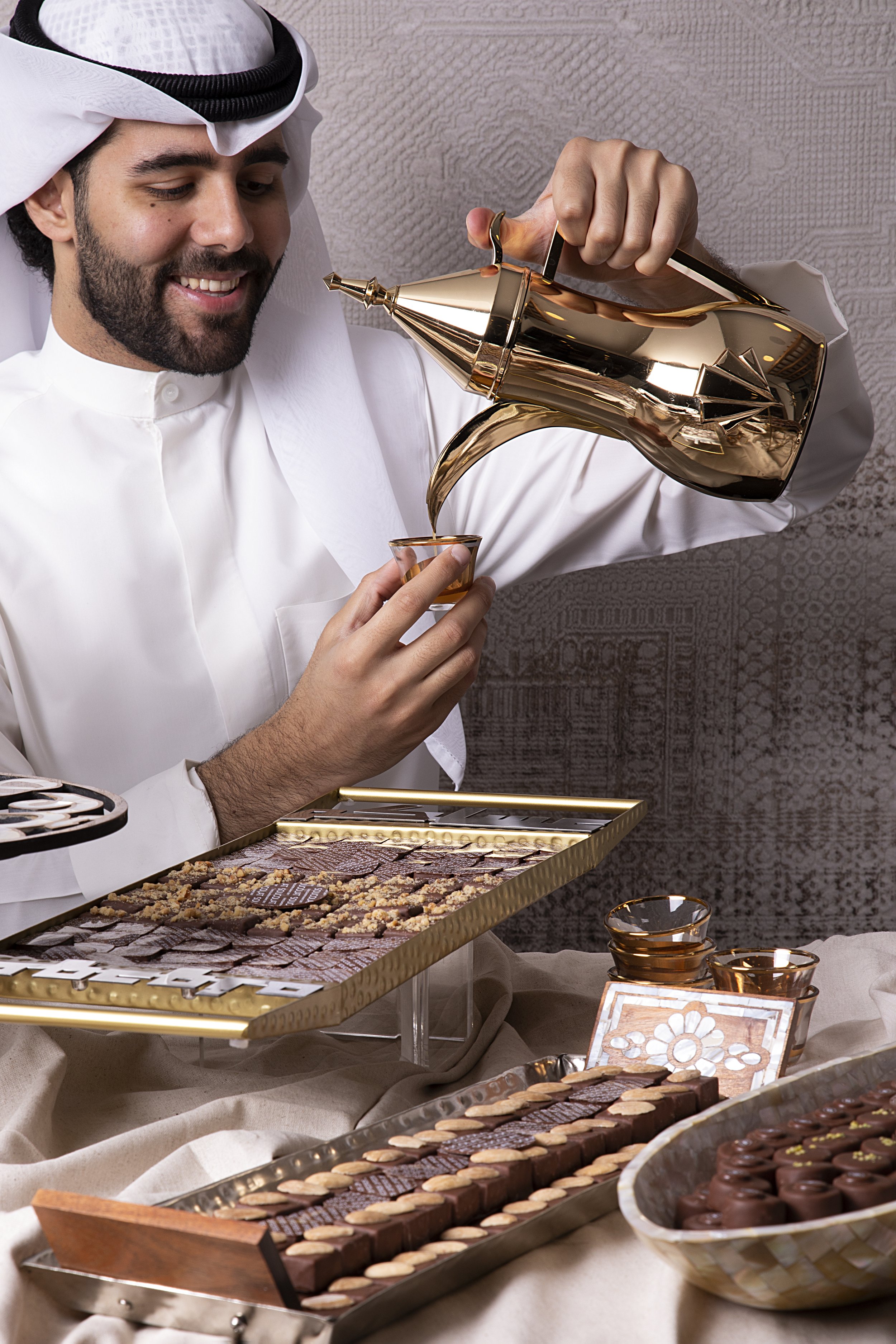 A man dressed in traditional Middle Eastern attire is pouring coffee