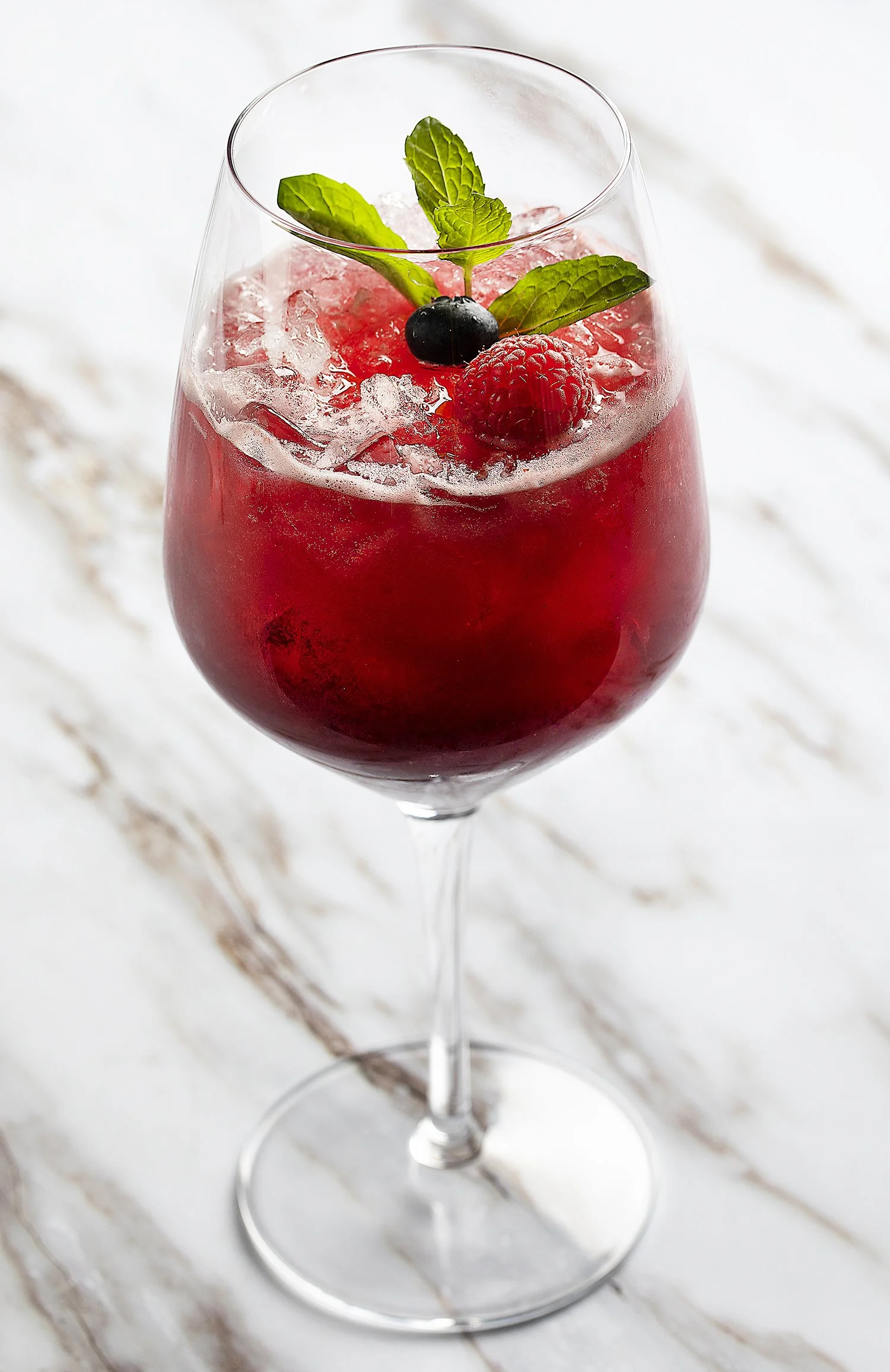 A wine glass filled with a red berry cocktail 