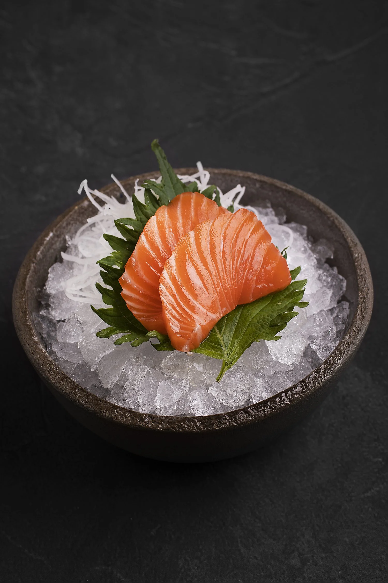 Slices of raw salmon sashimi on ice