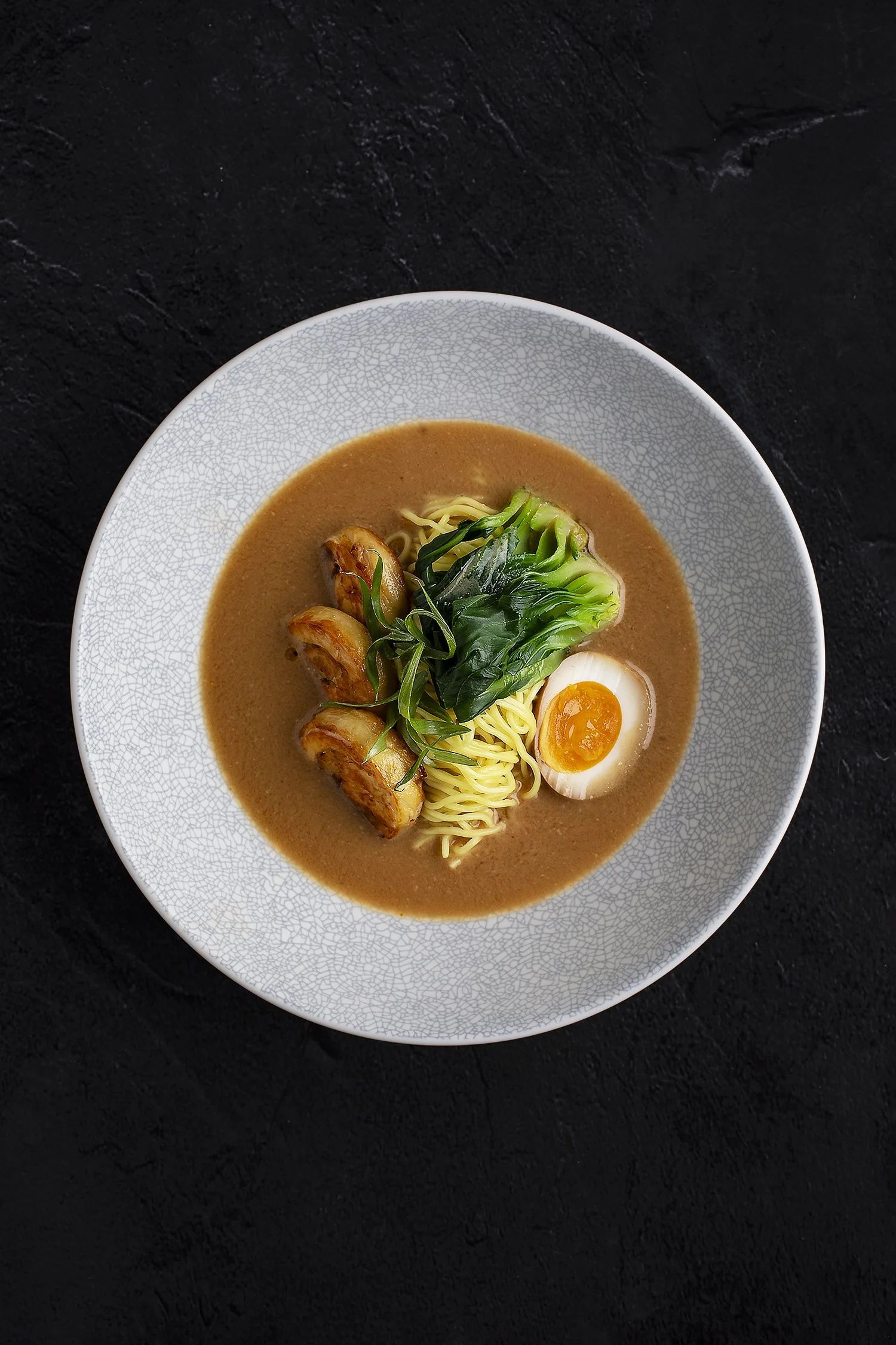 A bowl of ramen with broth, noodles, grilled chicken