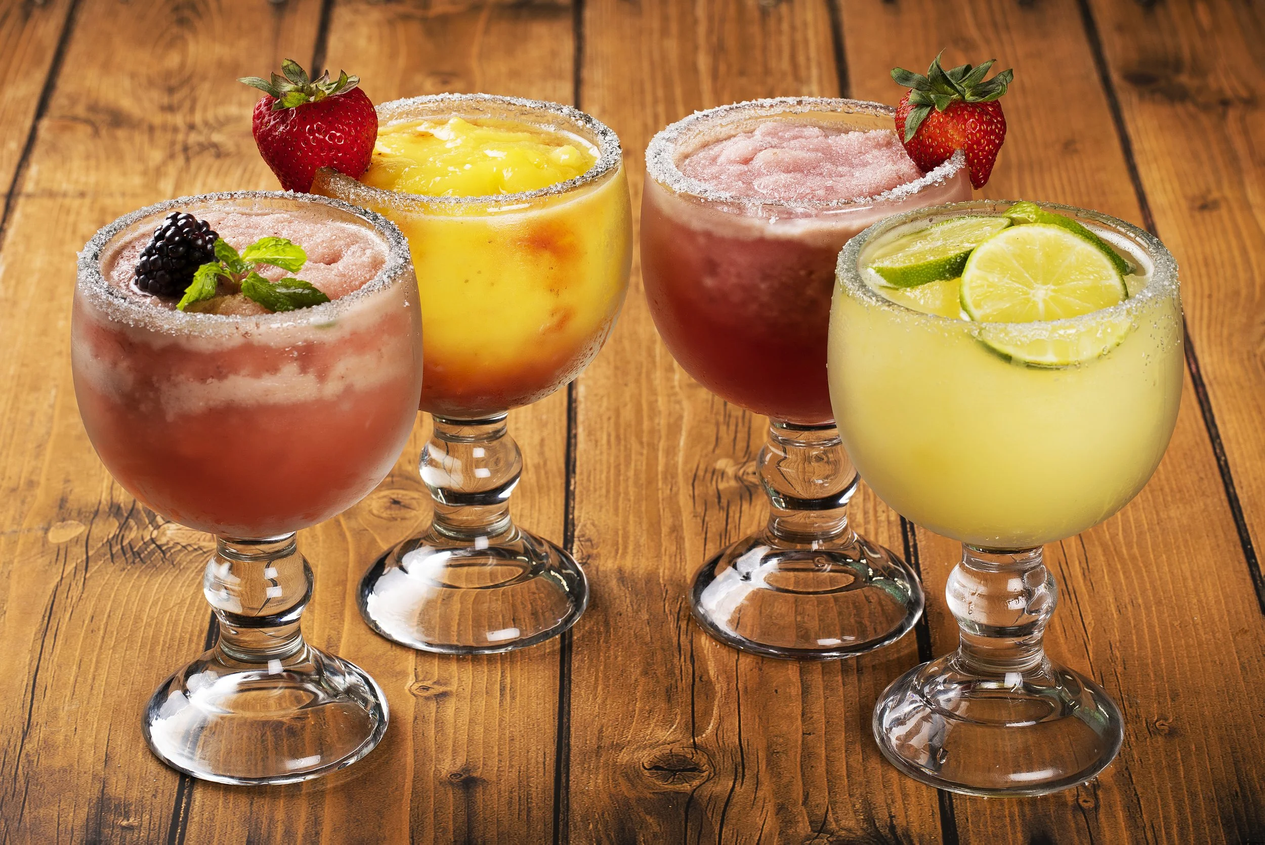 Four colorful frozen drinks in glass goblets
