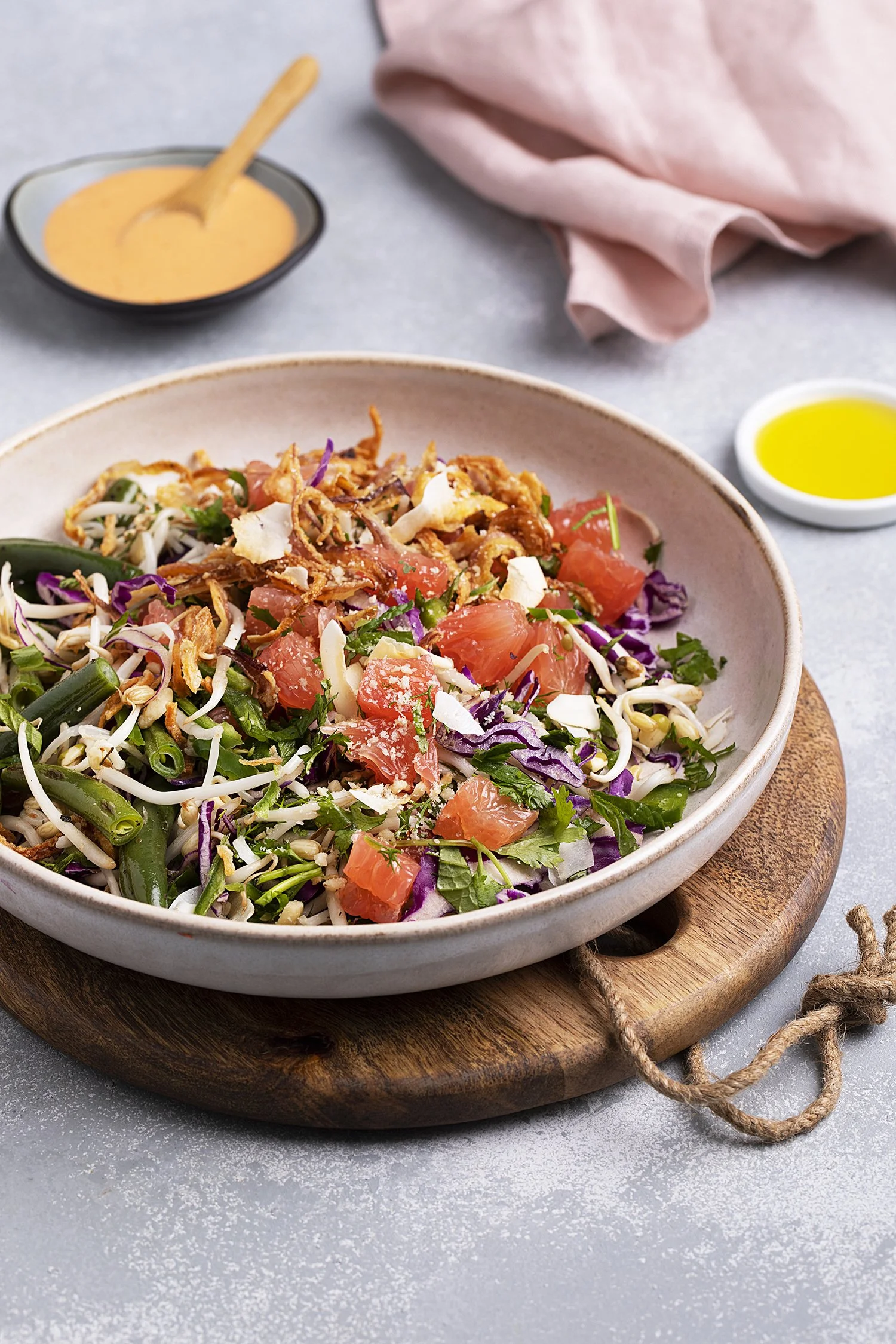 A bowl of salad with tomatoes, cabbage, green beans, onions, and crispy onions