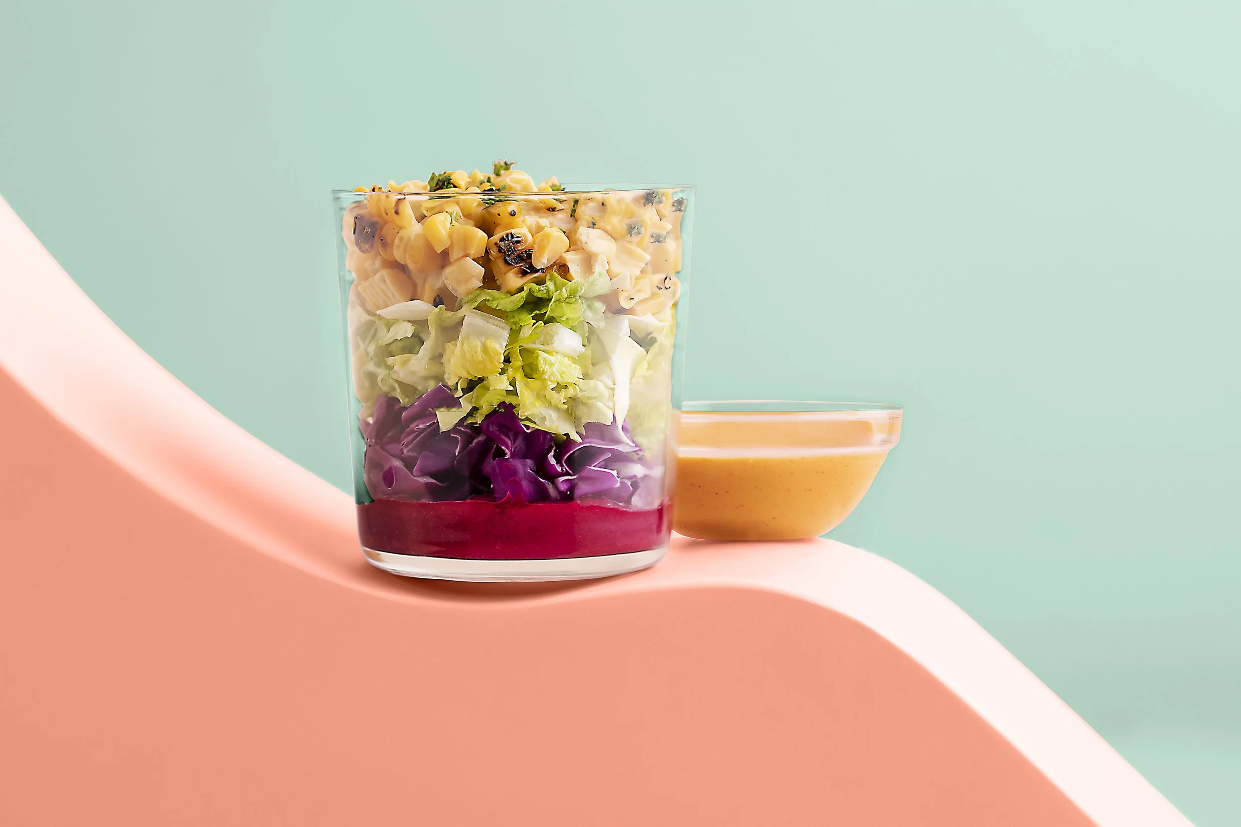 A layered salad in a clear glass bowl with shredded purple cabbage 