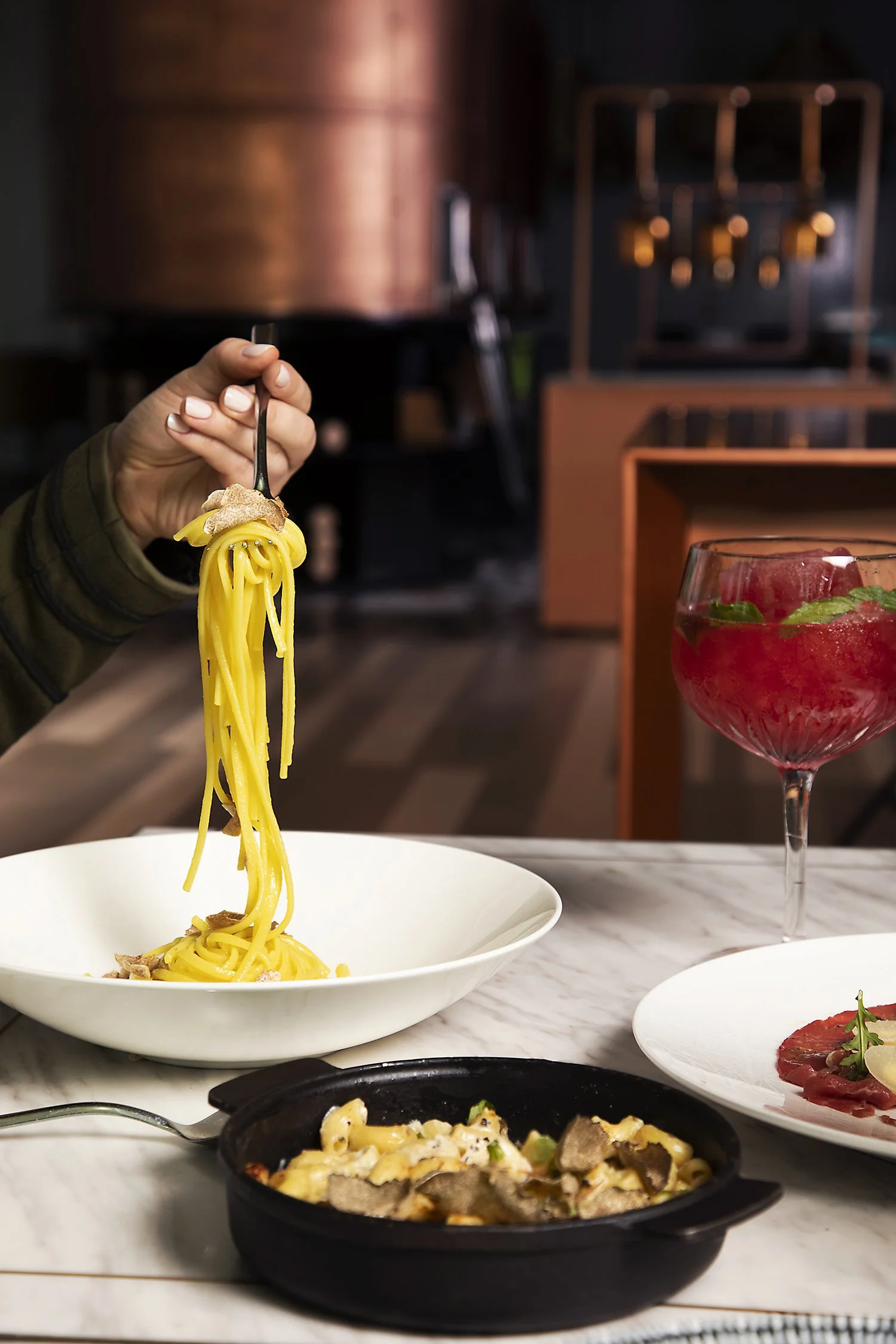 A person holding a fork serving of spaghetti