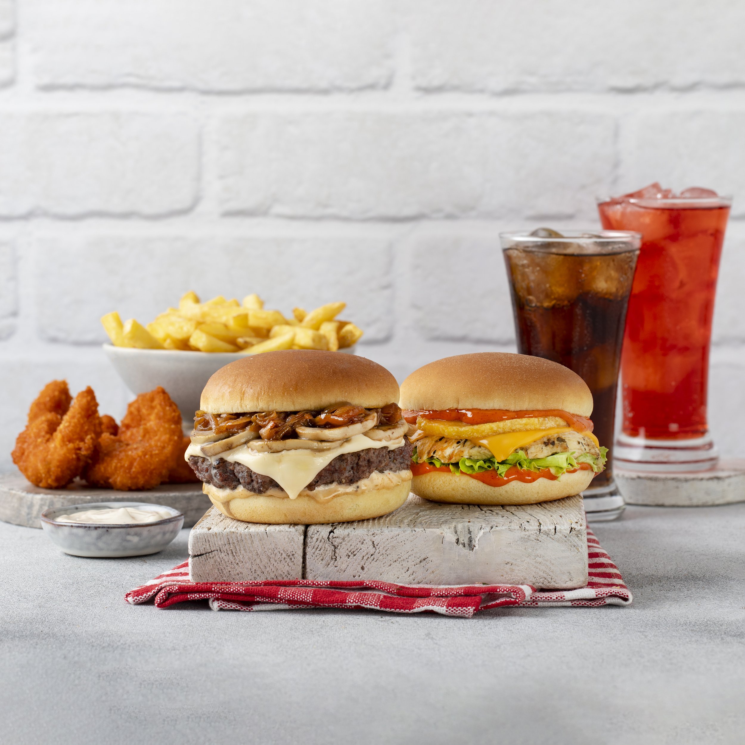 Two cheeseburgers, french fries, fried chicken pieces, and drinks