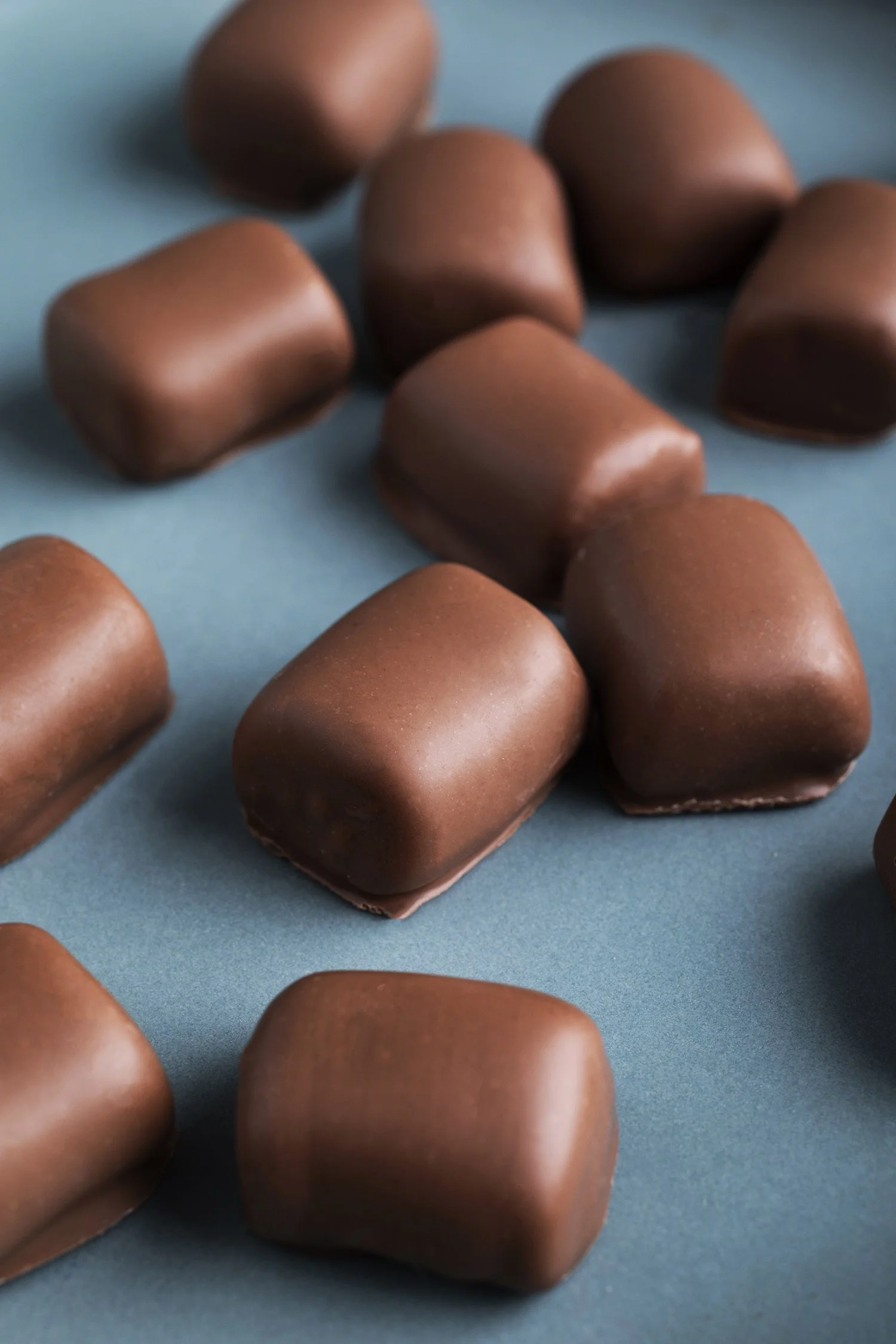 Close-up of several chocolates candies scattered on a blue surface. 
