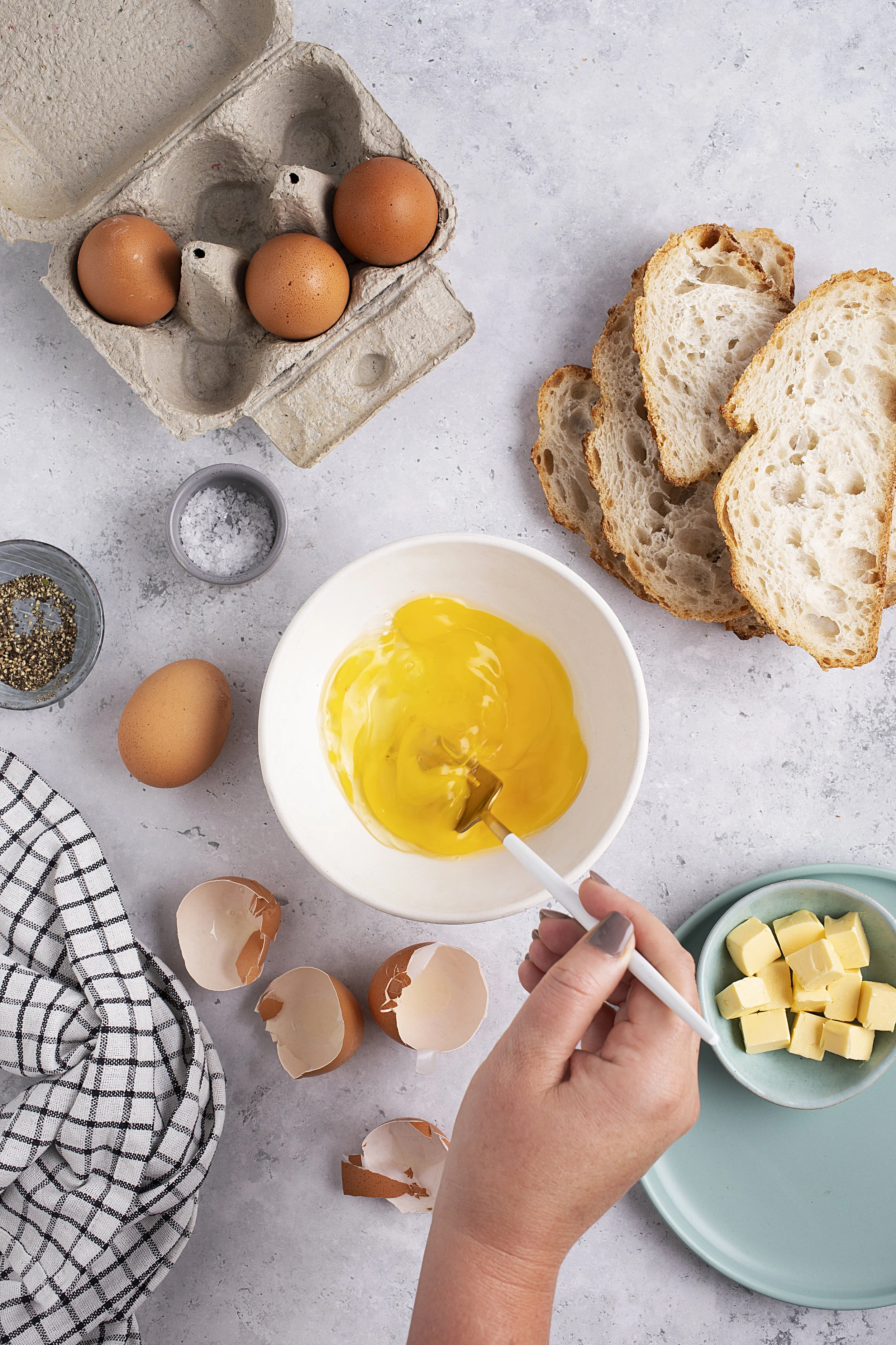 A person cracking eggs into a bowl