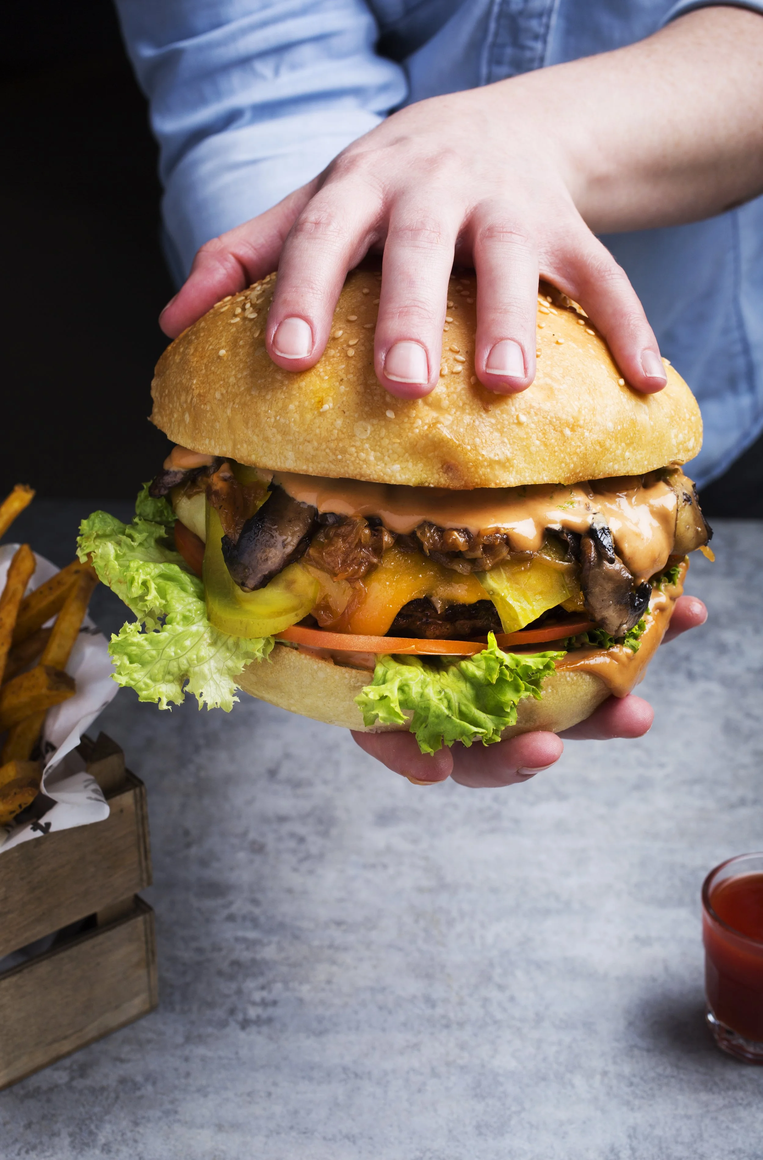 Person holding a large burger 