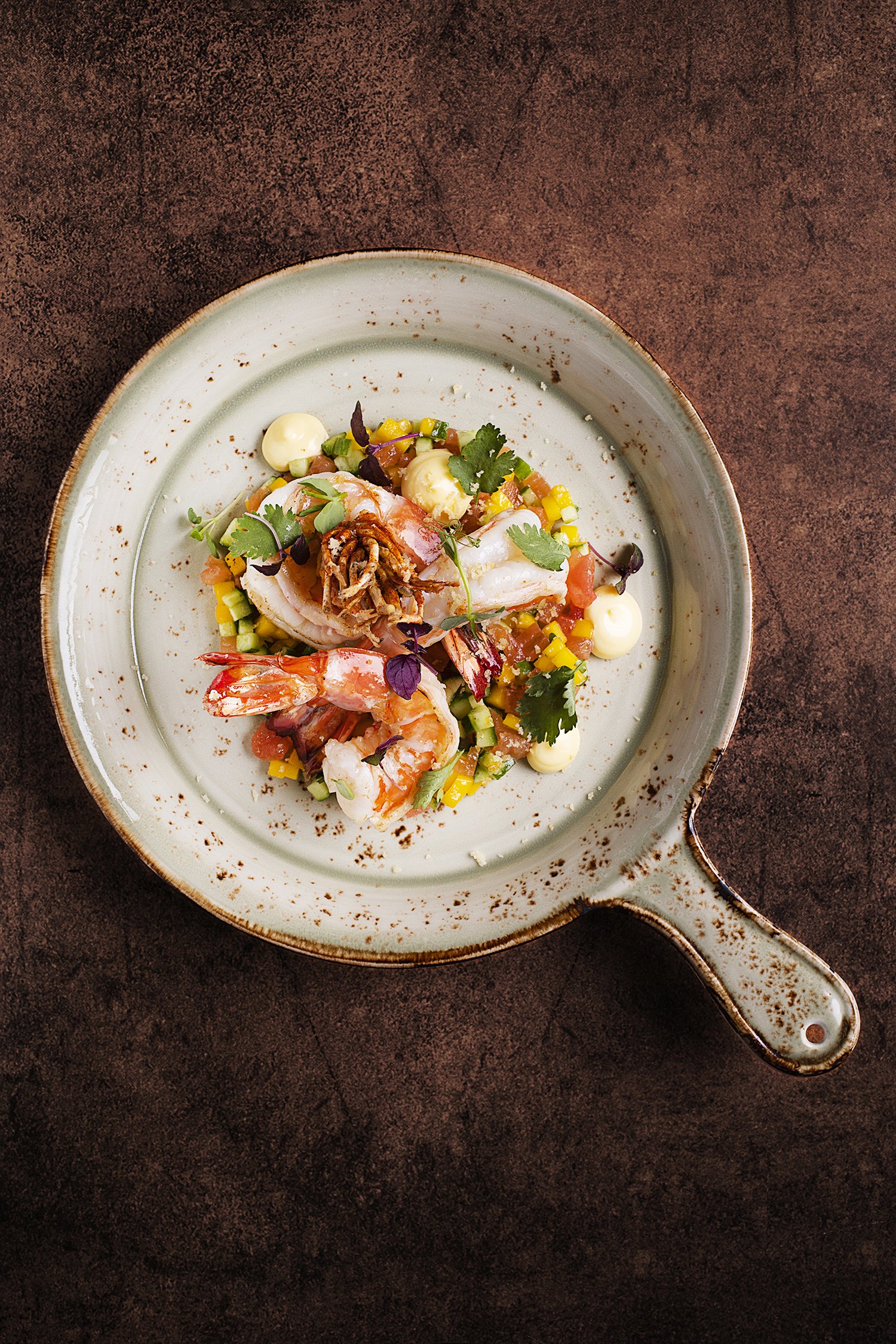 A plate of shrimp with vegetables and garnishes
