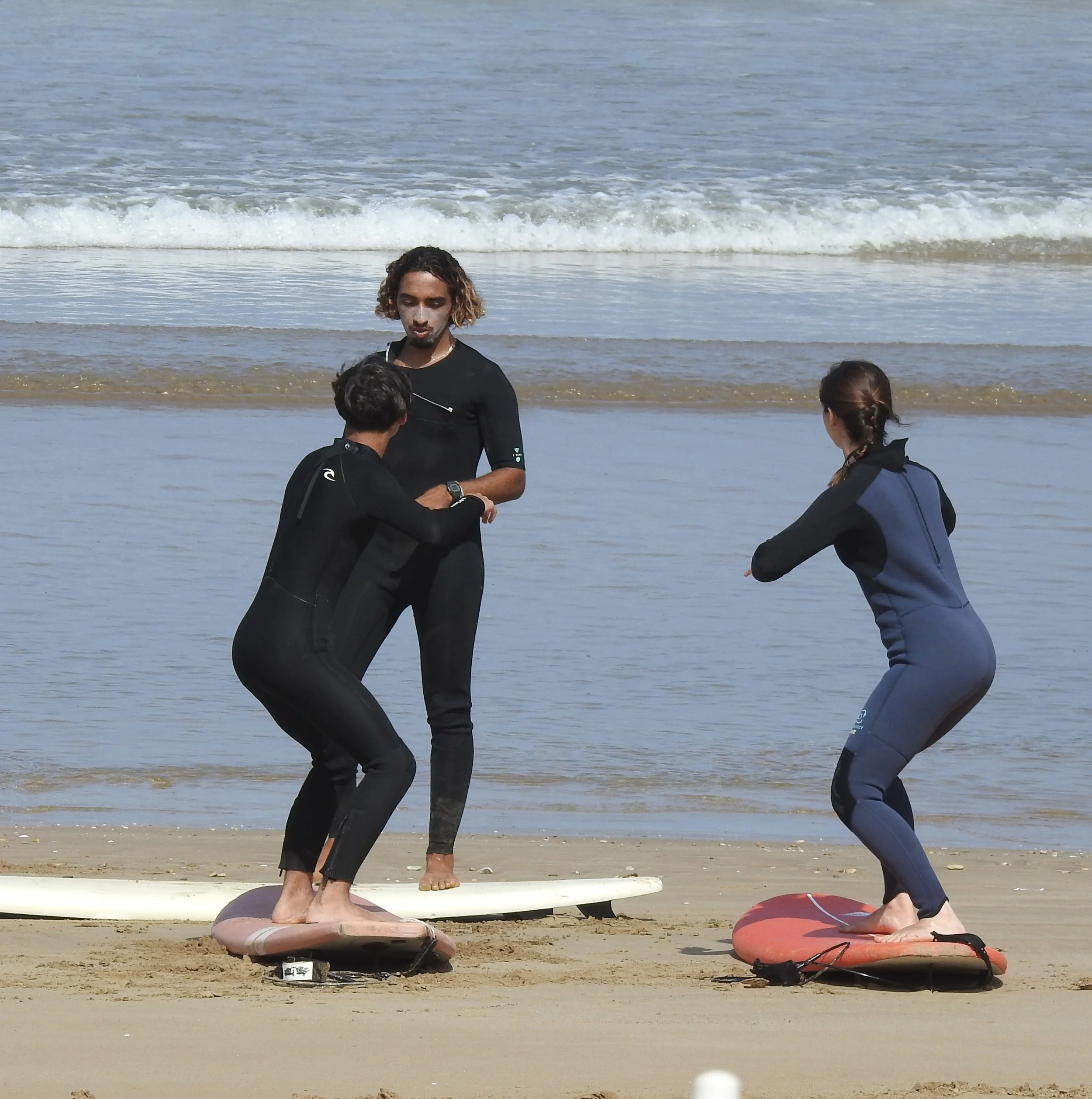 People at the beach with surfboards, preparing for surfing, with ocean waves in the background.