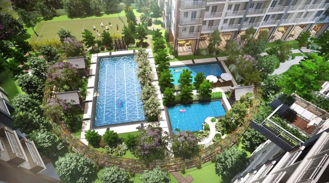 Aerial view of residential complex with three swimming pools, a tennis court, and lush green landscaping.