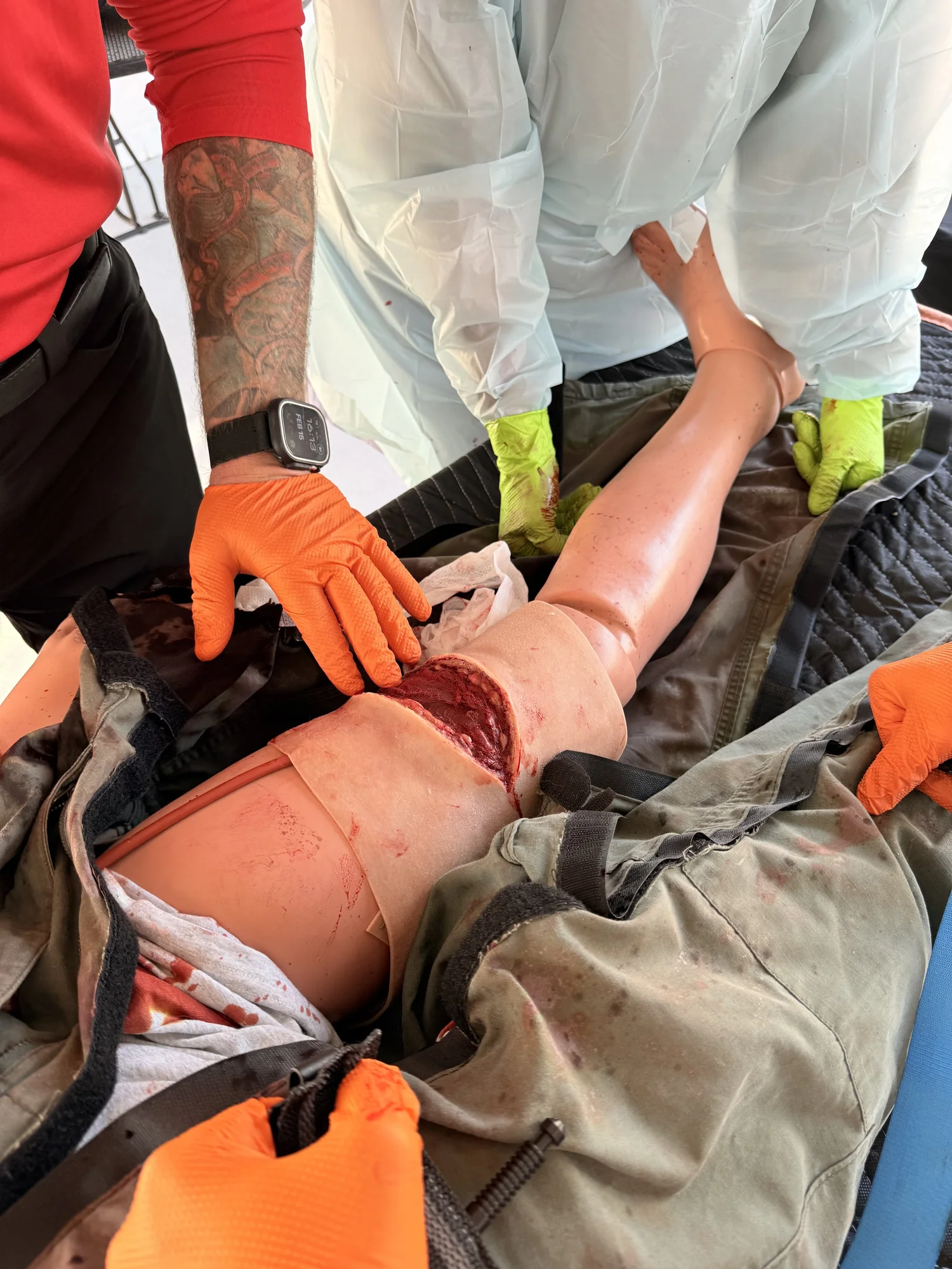 Gloved hands controlling bleeding on a trauma manikin during hands-on training