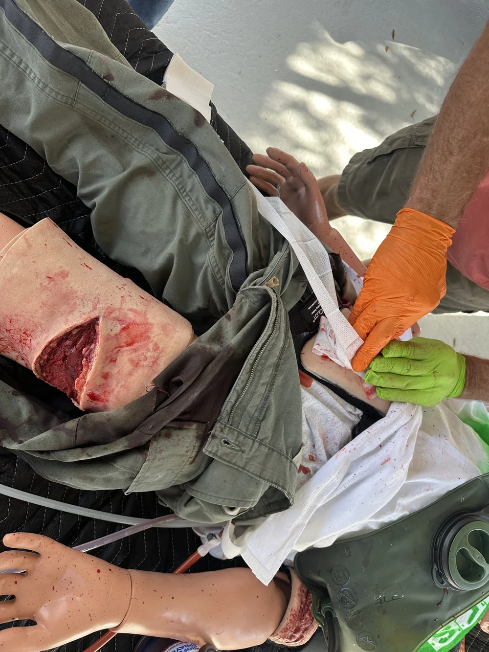 Students treating a leg wound on a trauma manikin during hands-on training