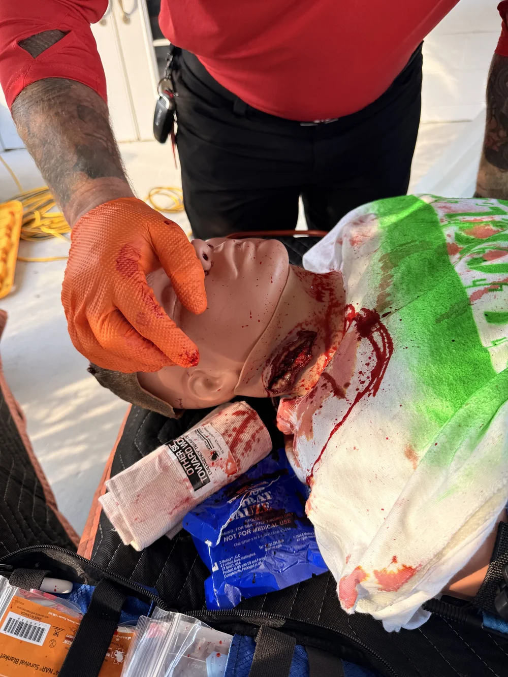 Gloved hands treating a head wound on a trauma manikin during the Civilian Trauma Course