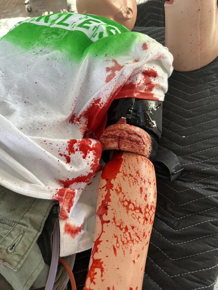 Tourniquet applied to a bleeding arm trainer during hands-on Stop the Bleed practice
