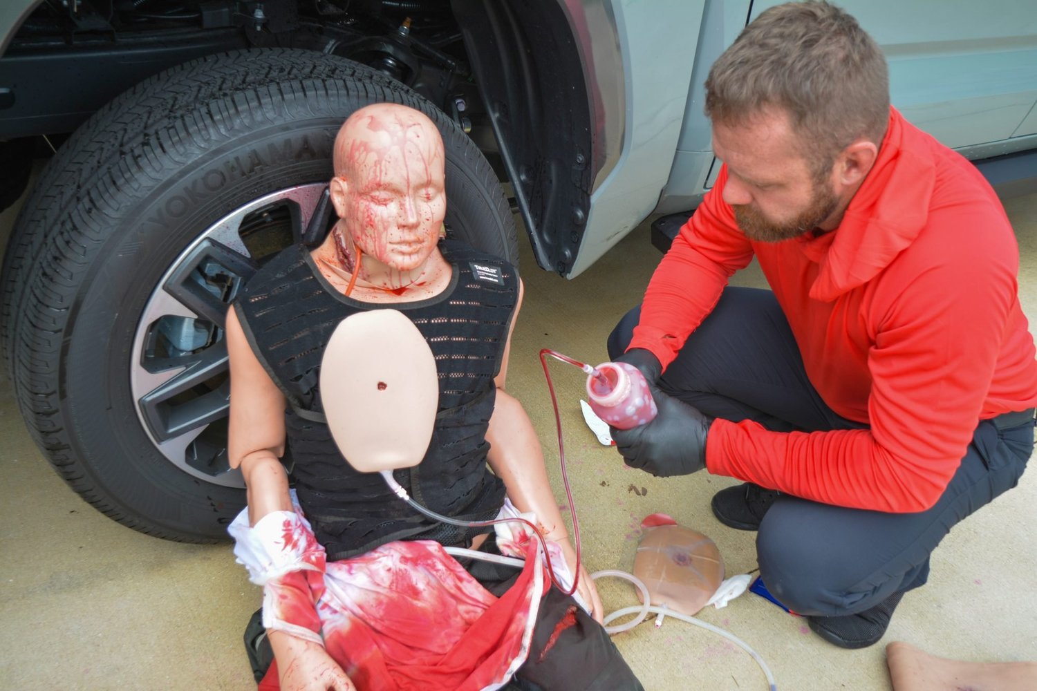 Ryan Kensinger treating a bleeding trauma manikin during a hands-on roadside scenario