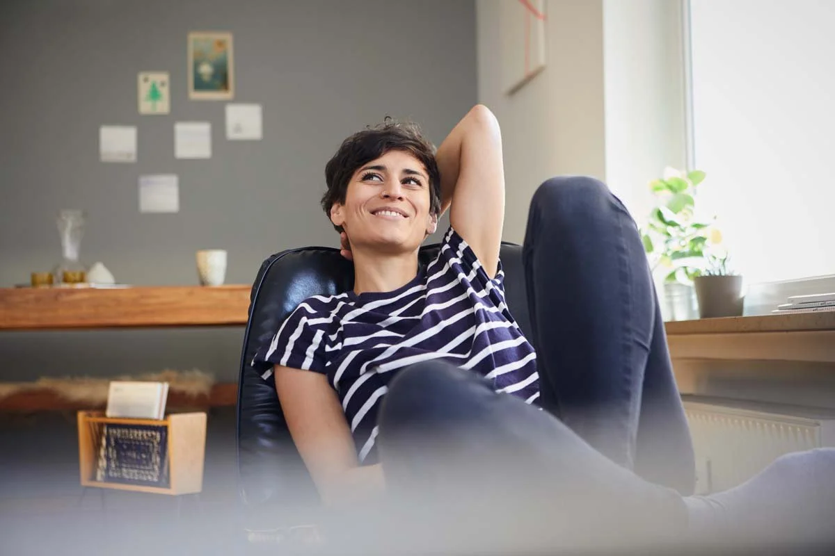Foto einer zufriedenen Frau die in ihrem Sessel sitzt