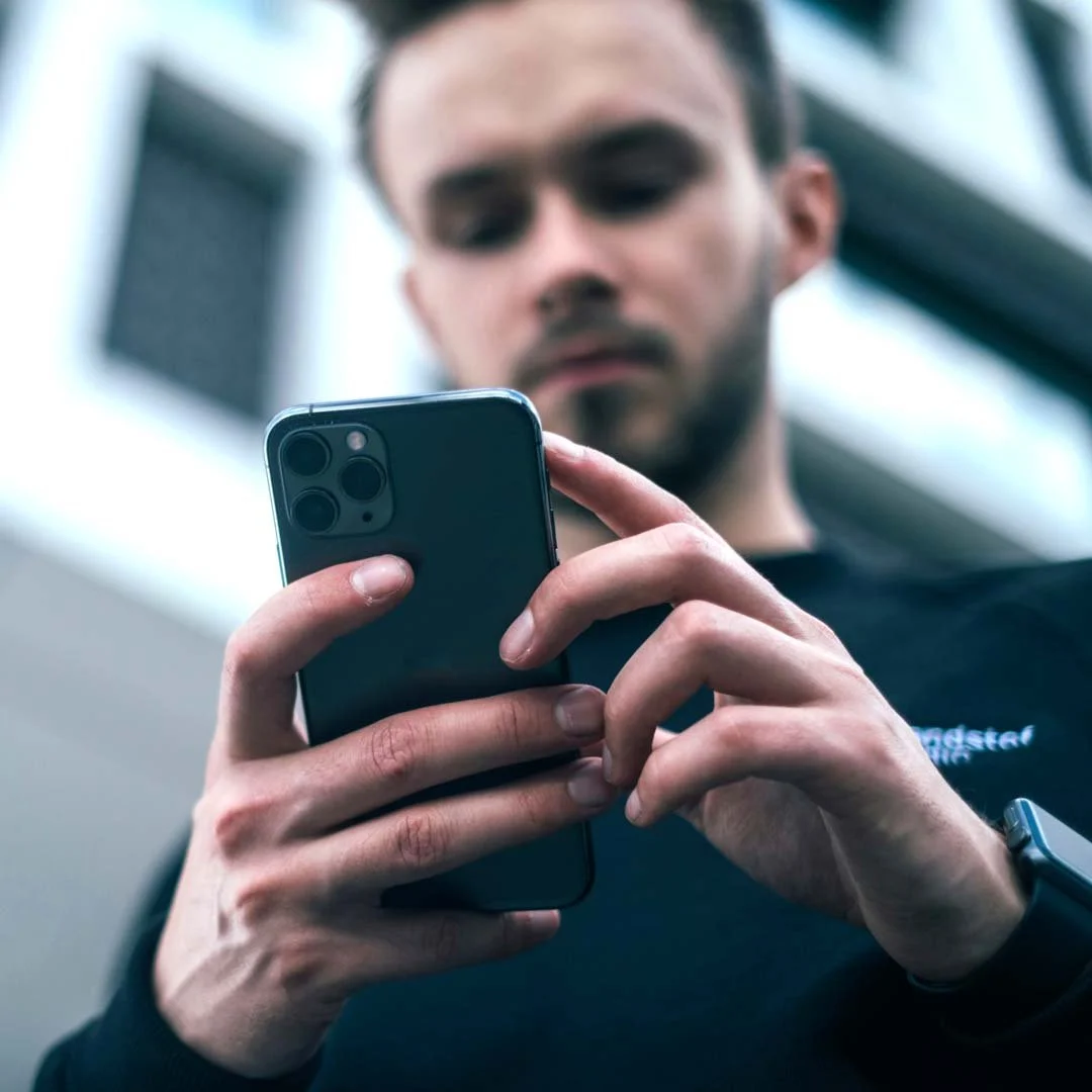 Foto eines Mannes, der auf sein iPhone schaut und etwas damit macht