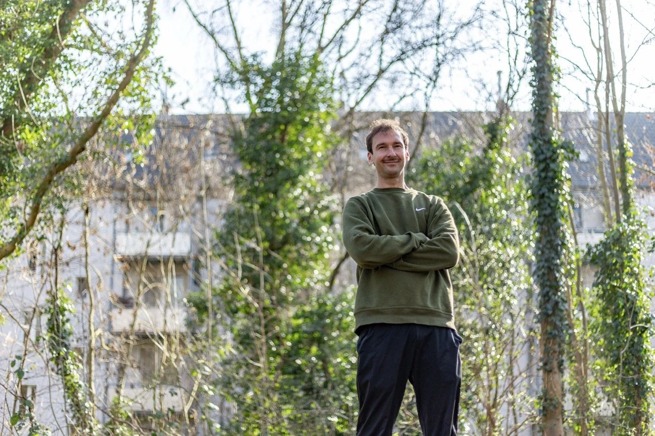 Thomas Ploch mit verschränkten Armen zwischen Bäumen stehend