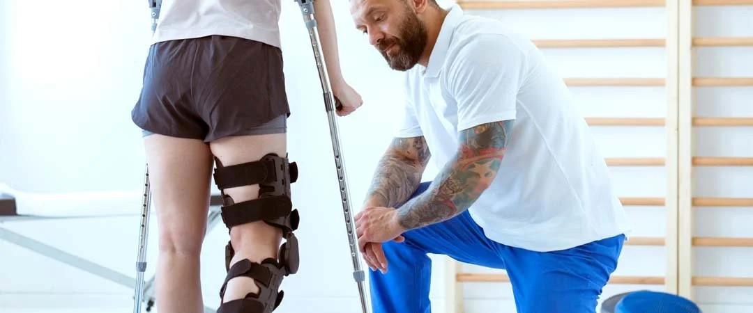 Foto eines Therapeuten, der eine Person mit Krücken therapiert