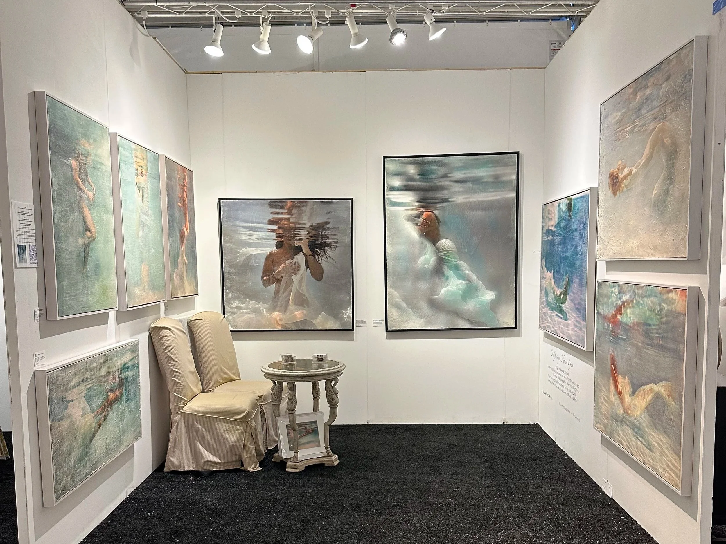 An art gallery display at the Hamptons FIne 
Art Show  featuring  Susan J Roche's encaustic mixed-media, with typical gallery lighting and furnishings.