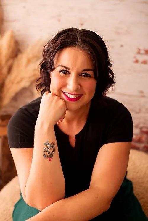A young man in a gray polo shirt and cream-colored pants sitting on a bench against a beige wall, casting a shadow behind him.
