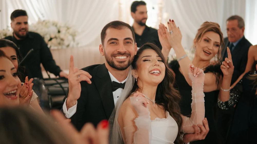 Newlyweds smiling among cheering wedding guests.